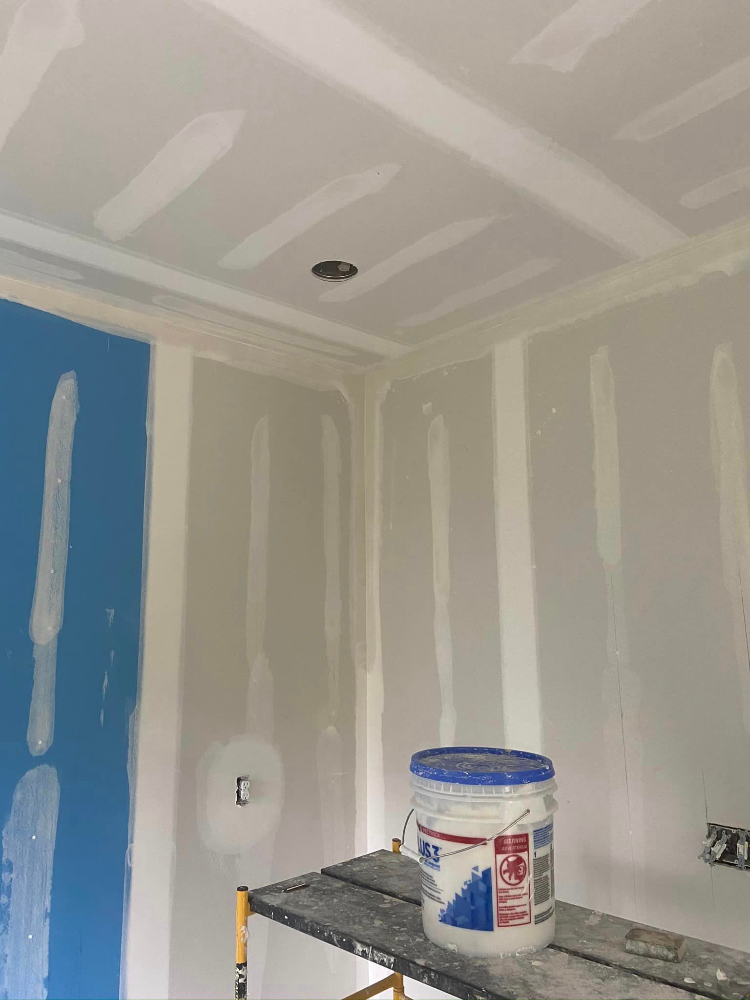 A bucket of paint is sitting on a scaffolding in a room.