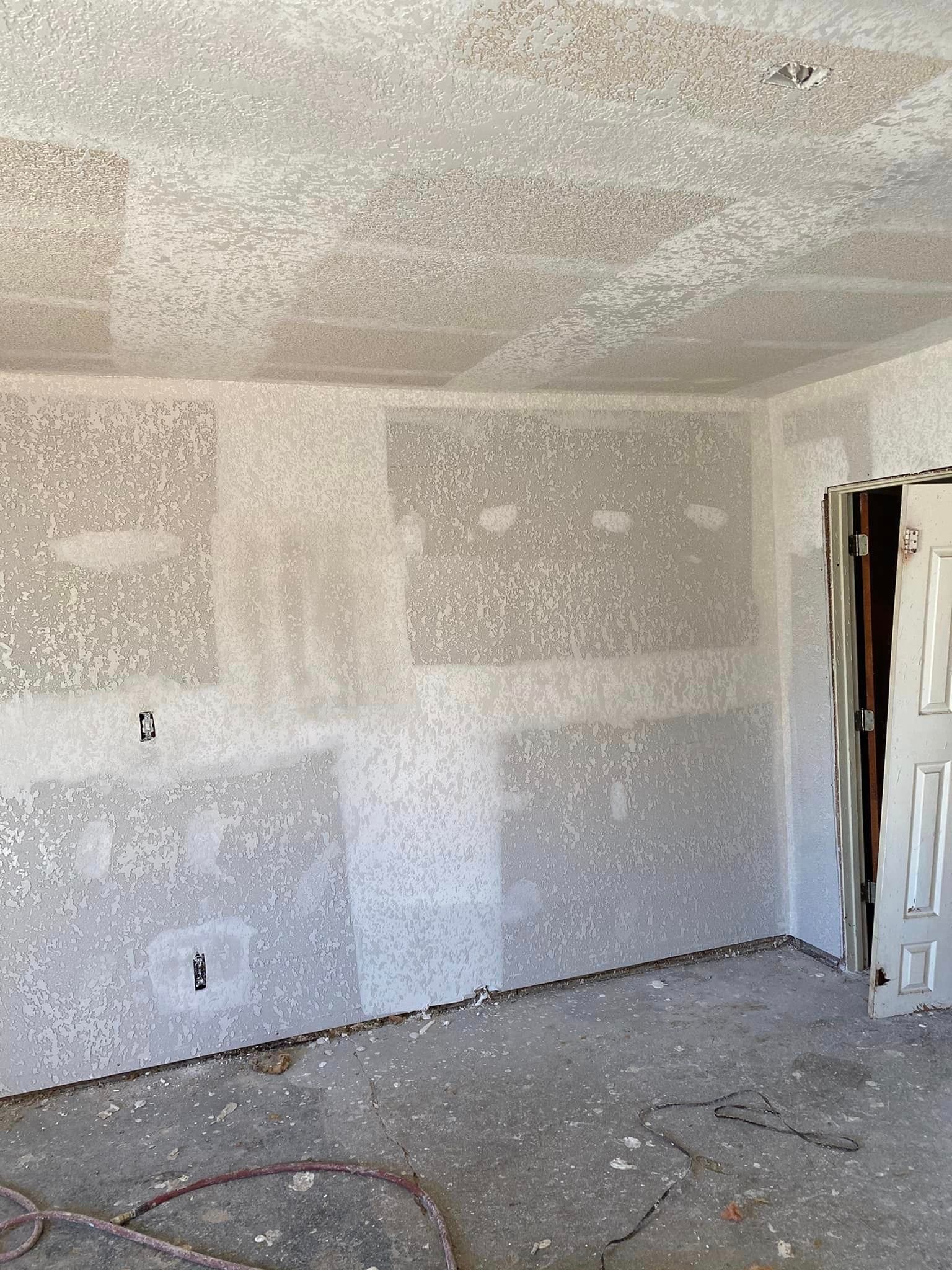 A room with drywall on the walls and a door.