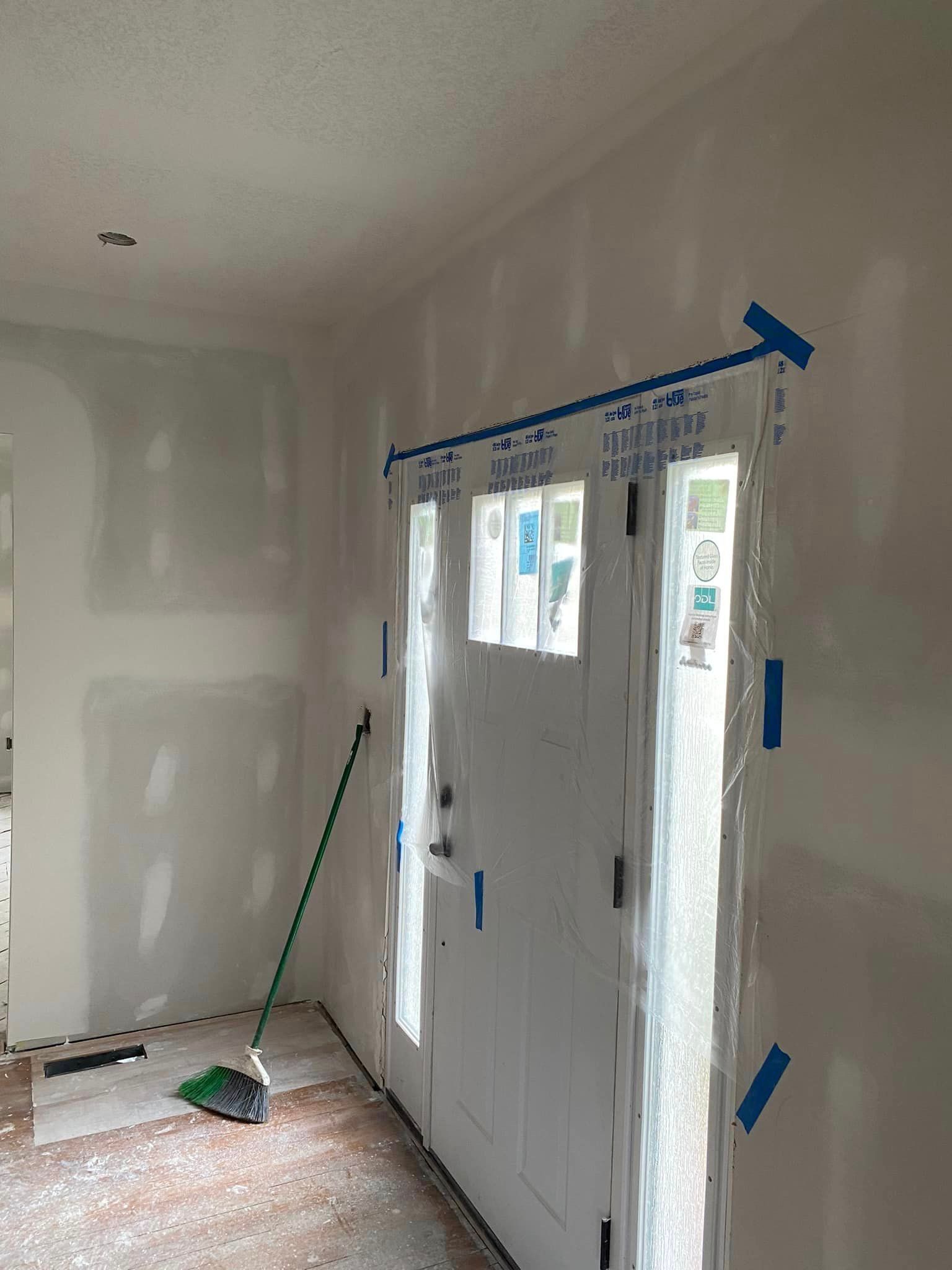 A room with a door and a broom in it.