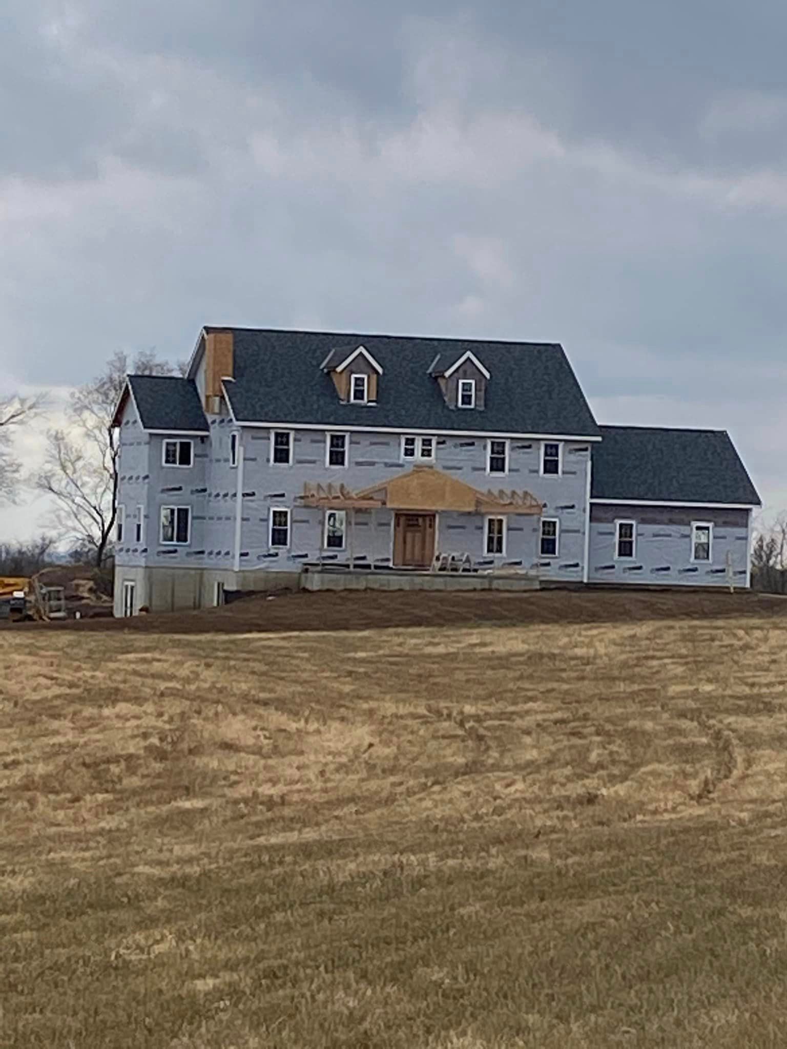 A large house is being built in the middle of a field.