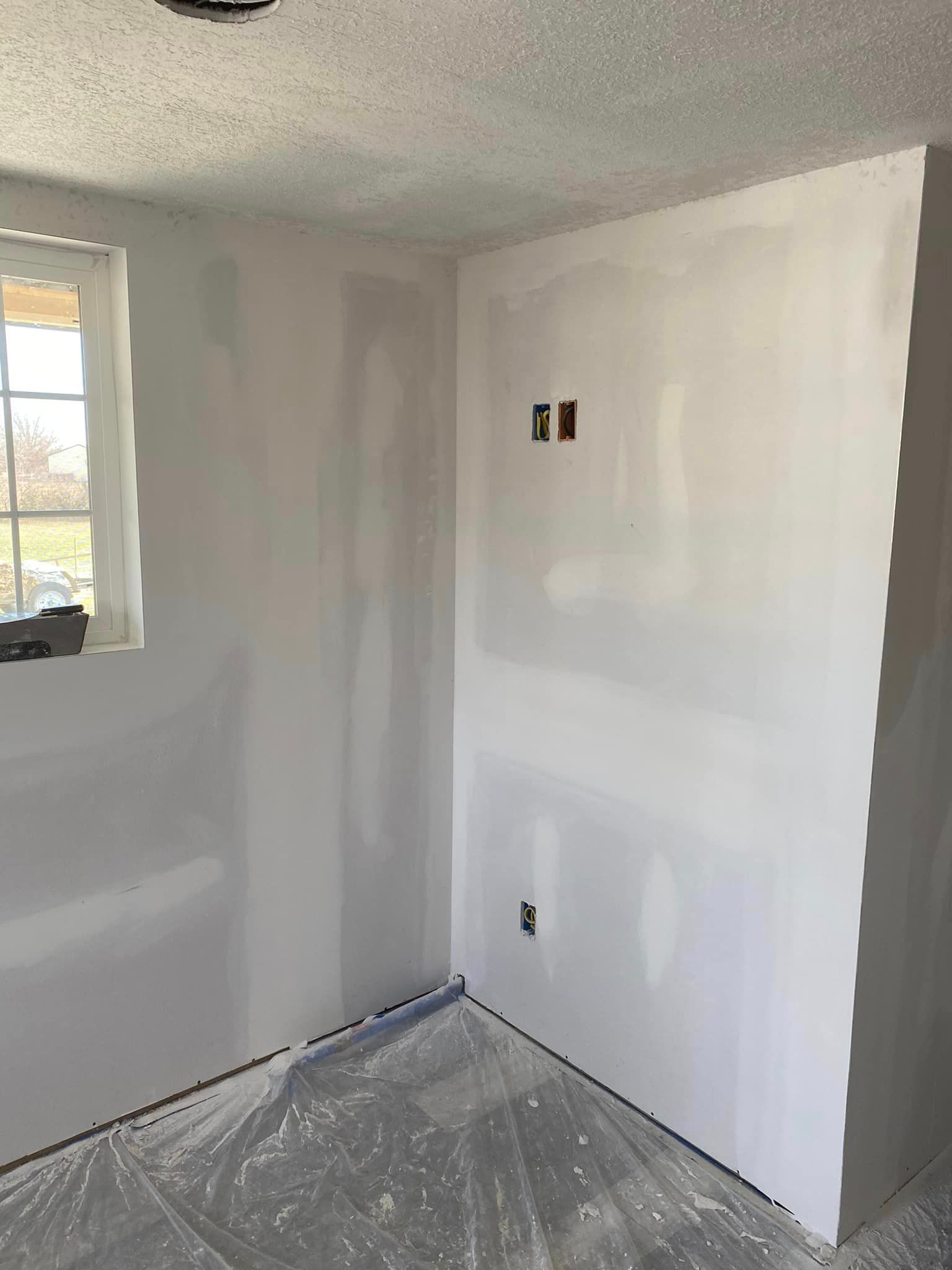 A room with white walls and a window is being remodeled.