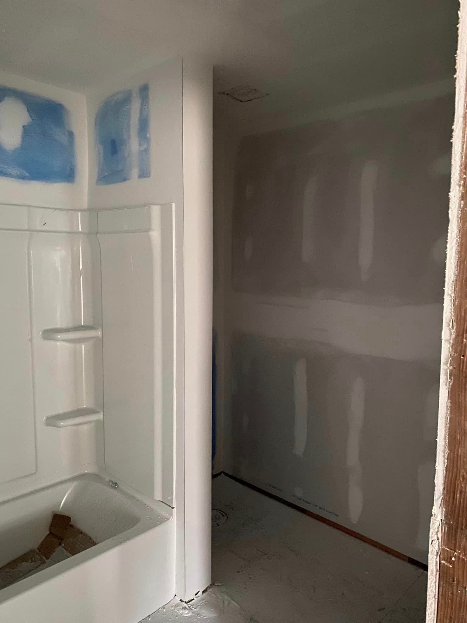 A bathroom under construction with a bathtub and shower stall.