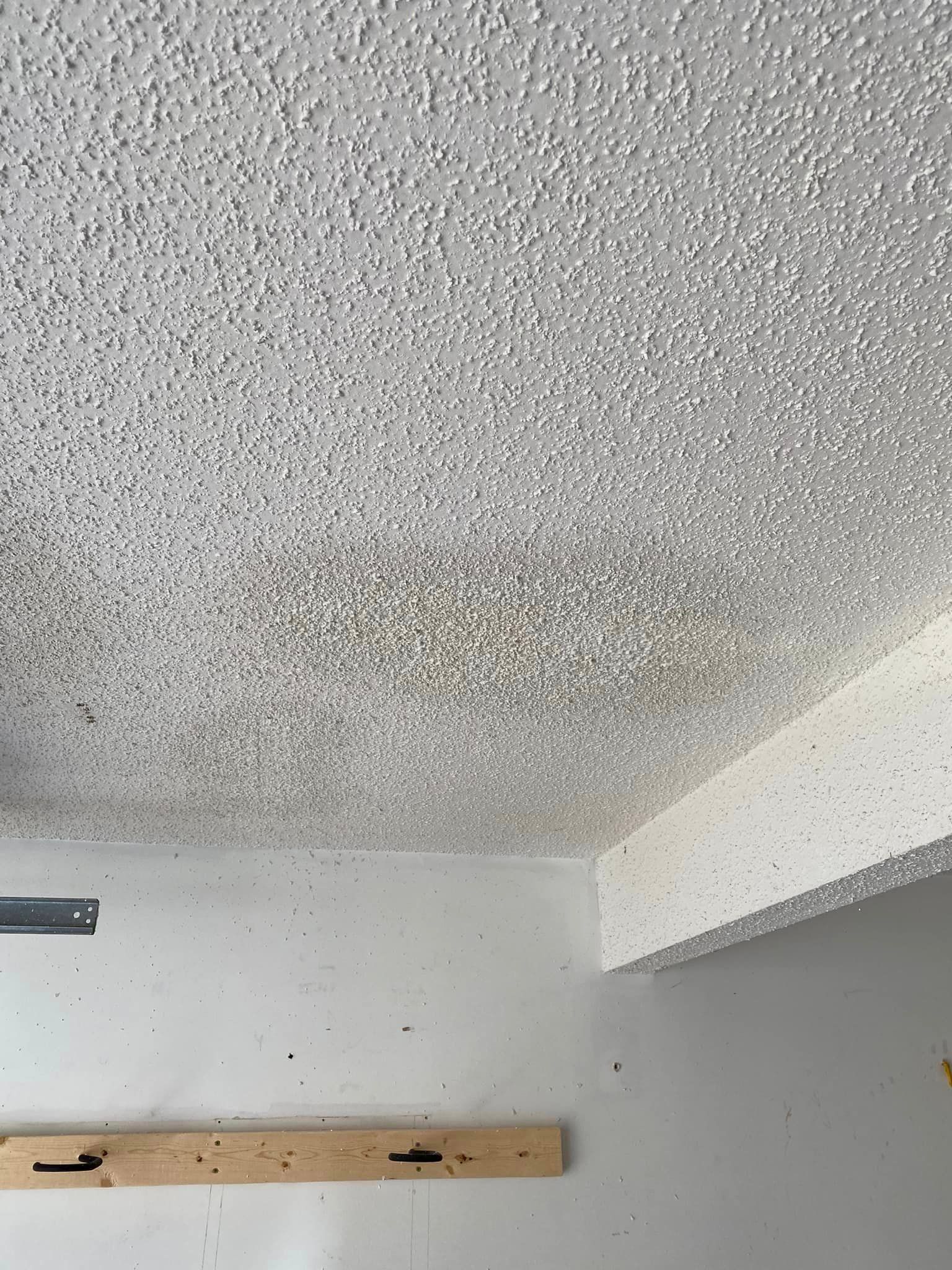 A close up of a ceiling with a wooden shelf in a room.