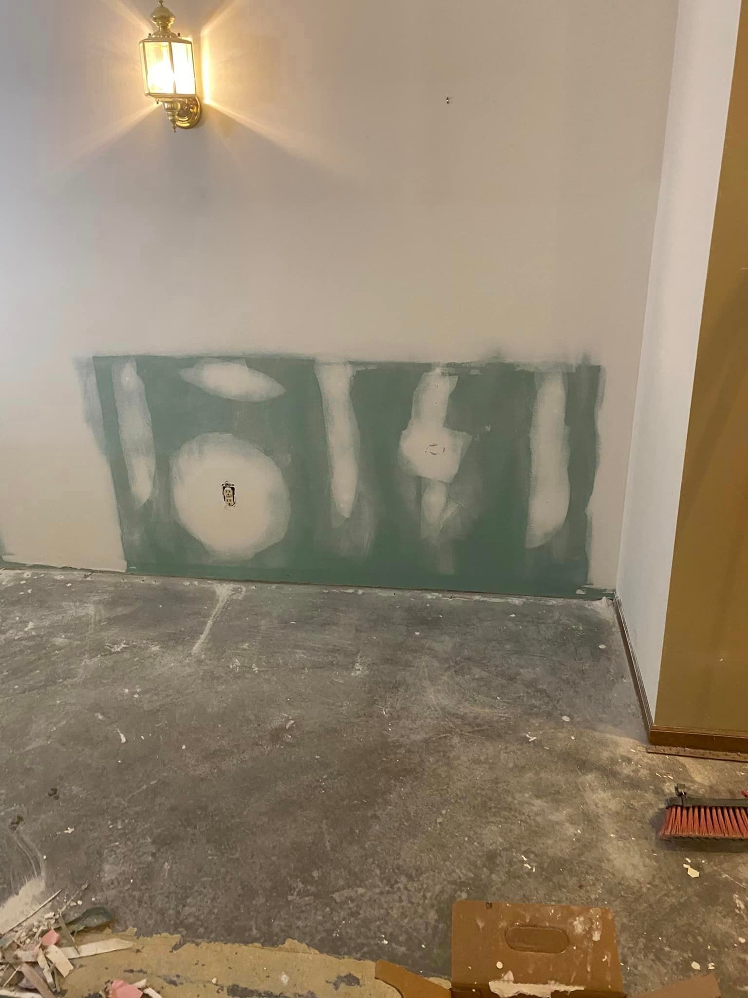 A room with a wall that is being painted and a light on the wall.