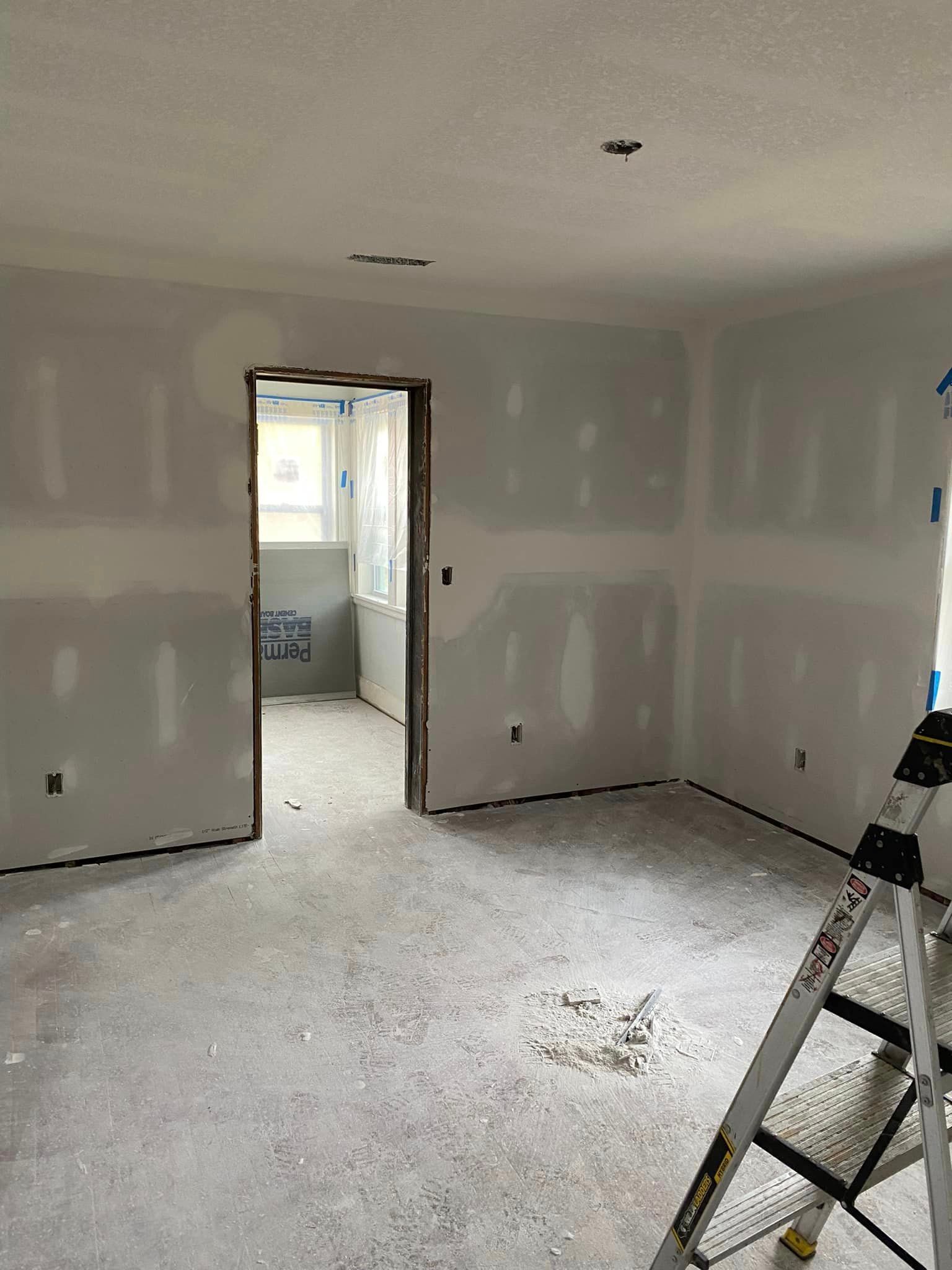 A room with drywall and a ladder in it.