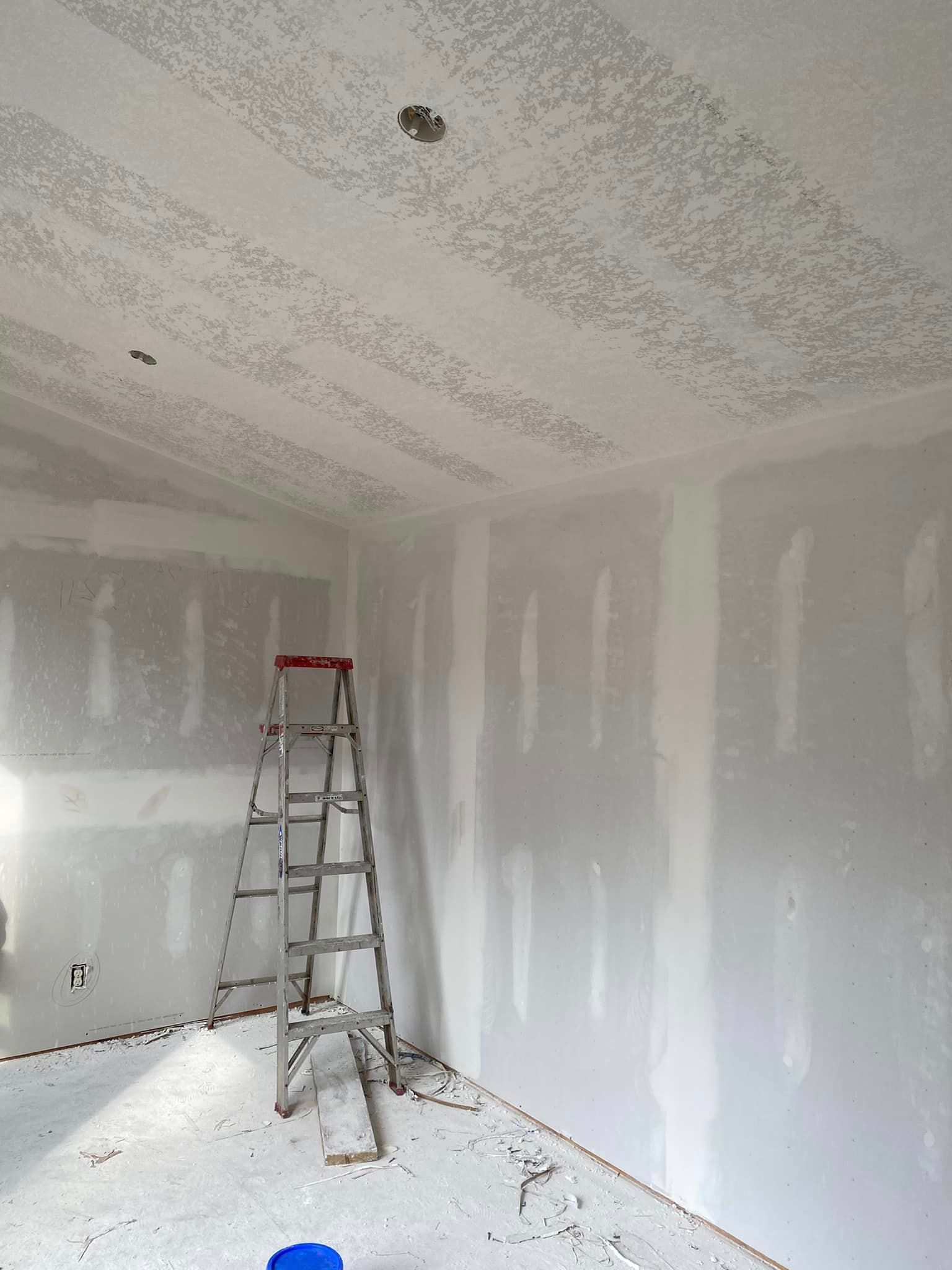 A room with drywall and a ladder in the corner.