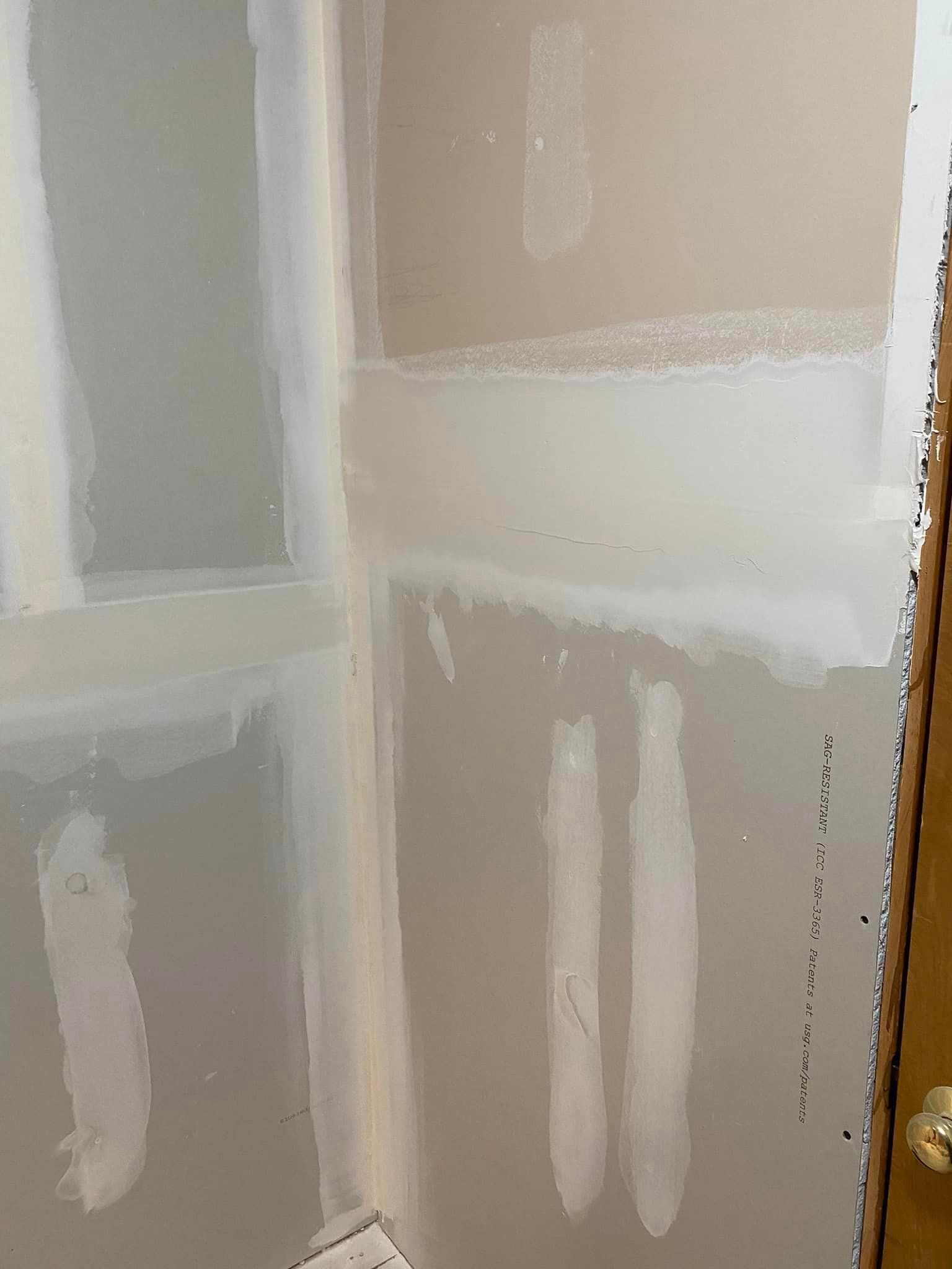A corner of a room with drywall and a door.