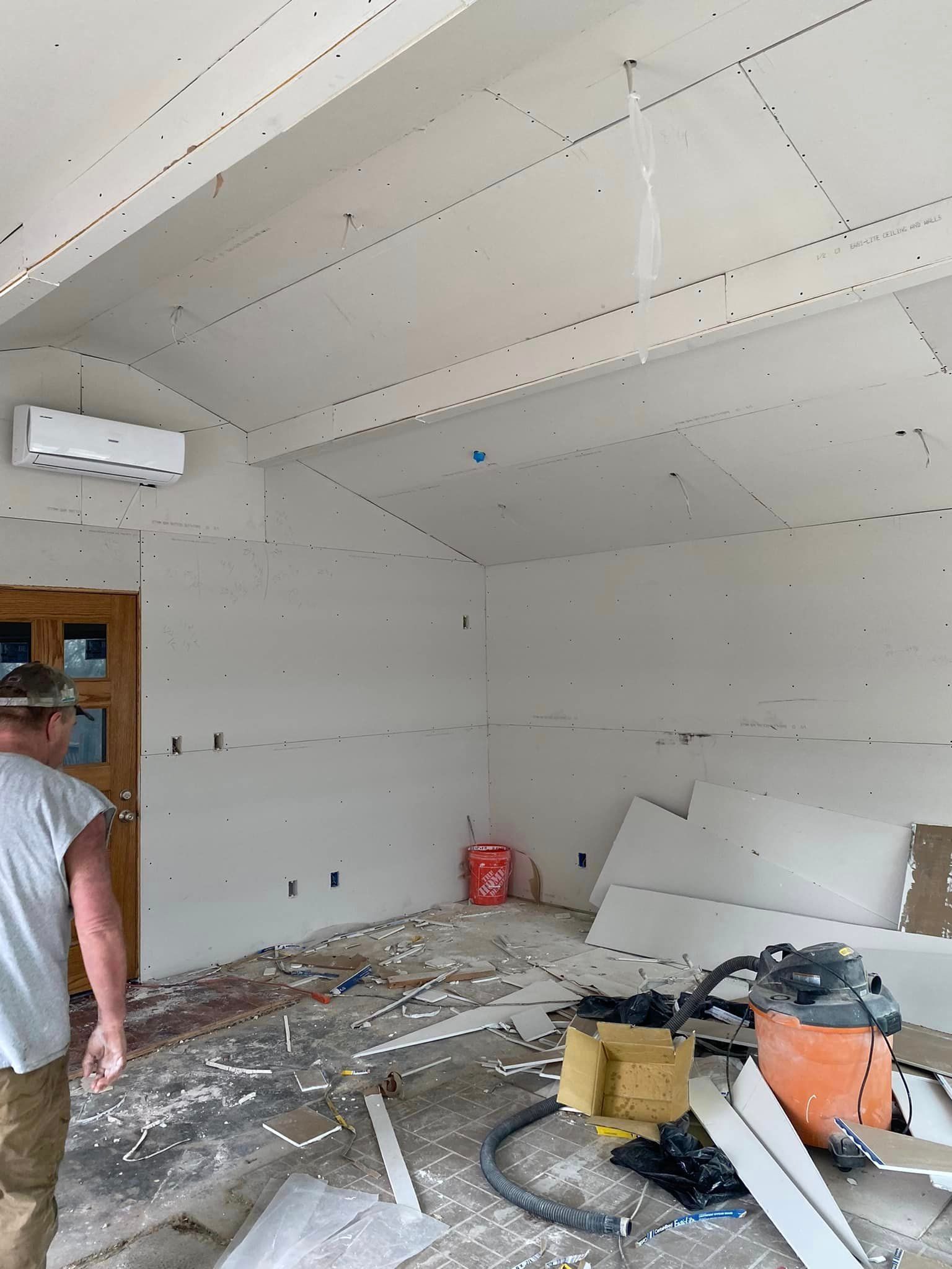 A man is standing in a room with a vacuum cleaner.