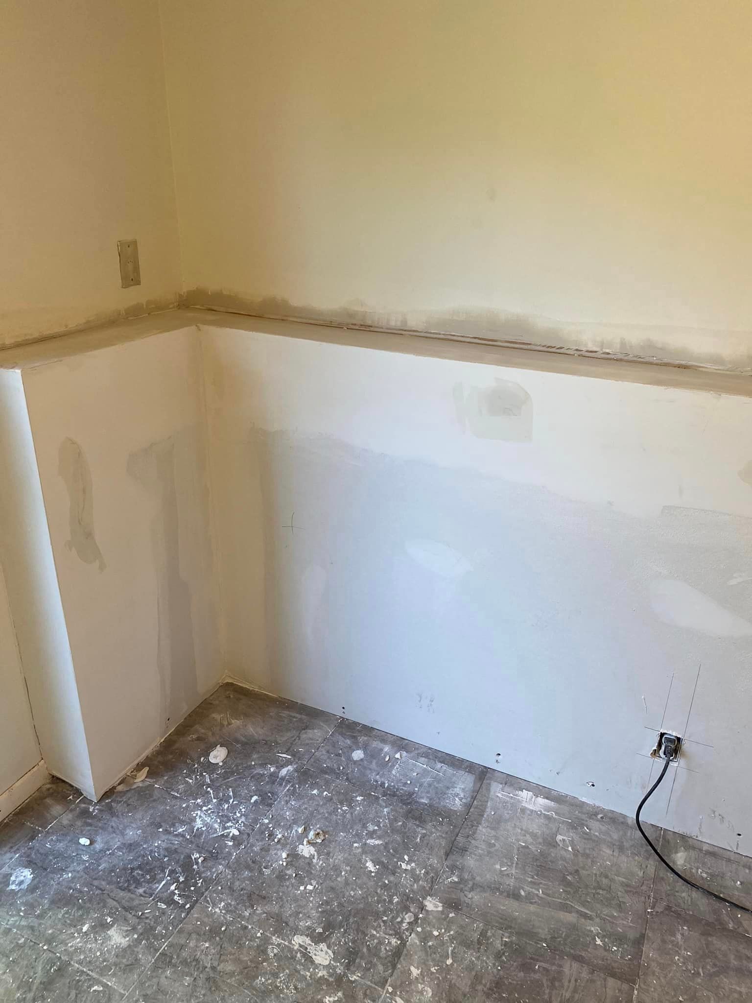 A room with a white wall and a gray floor.