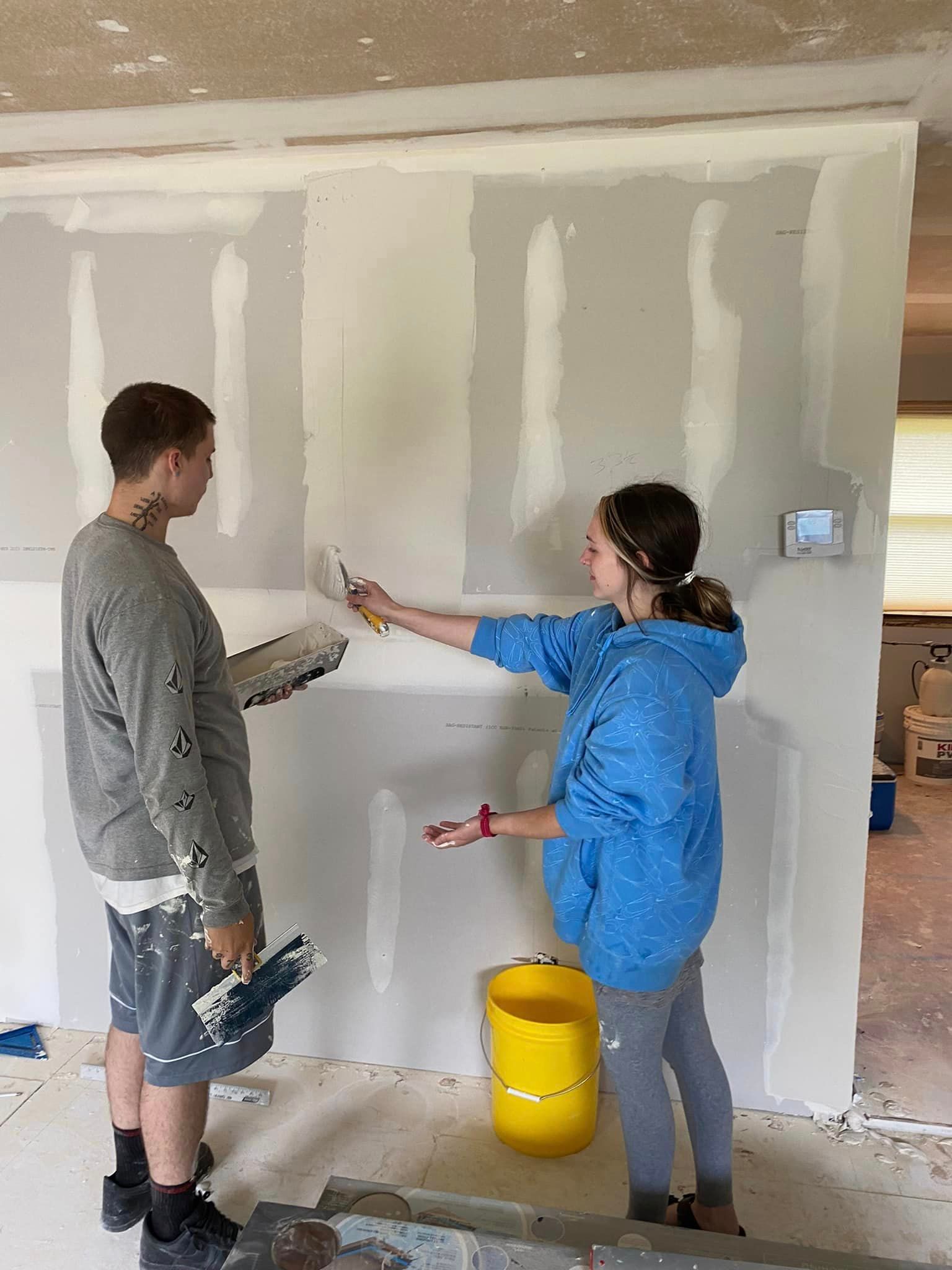 A man and a woman are painting a wall together.