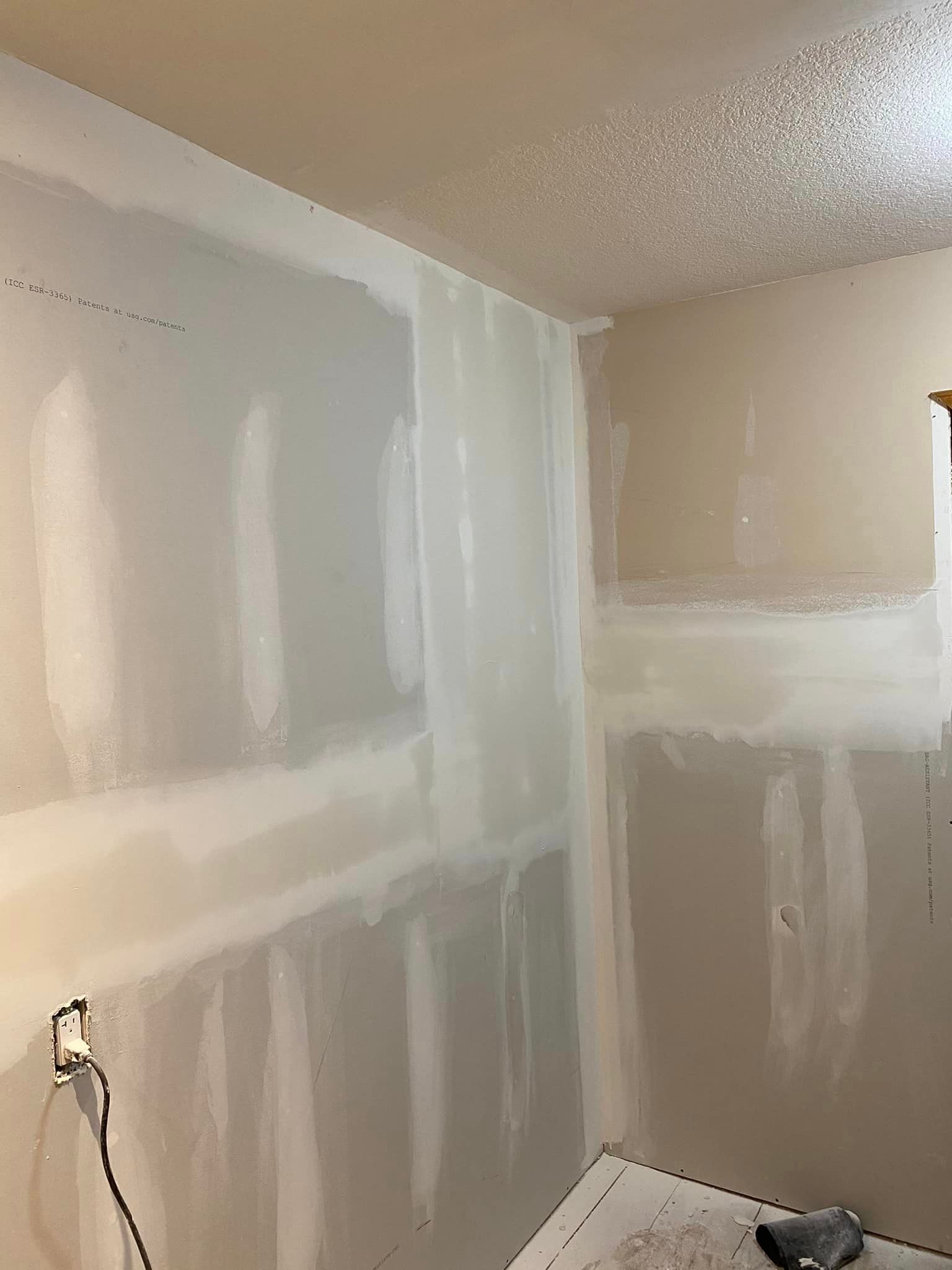 A room with drywall walls and a ceiling is being painted.
