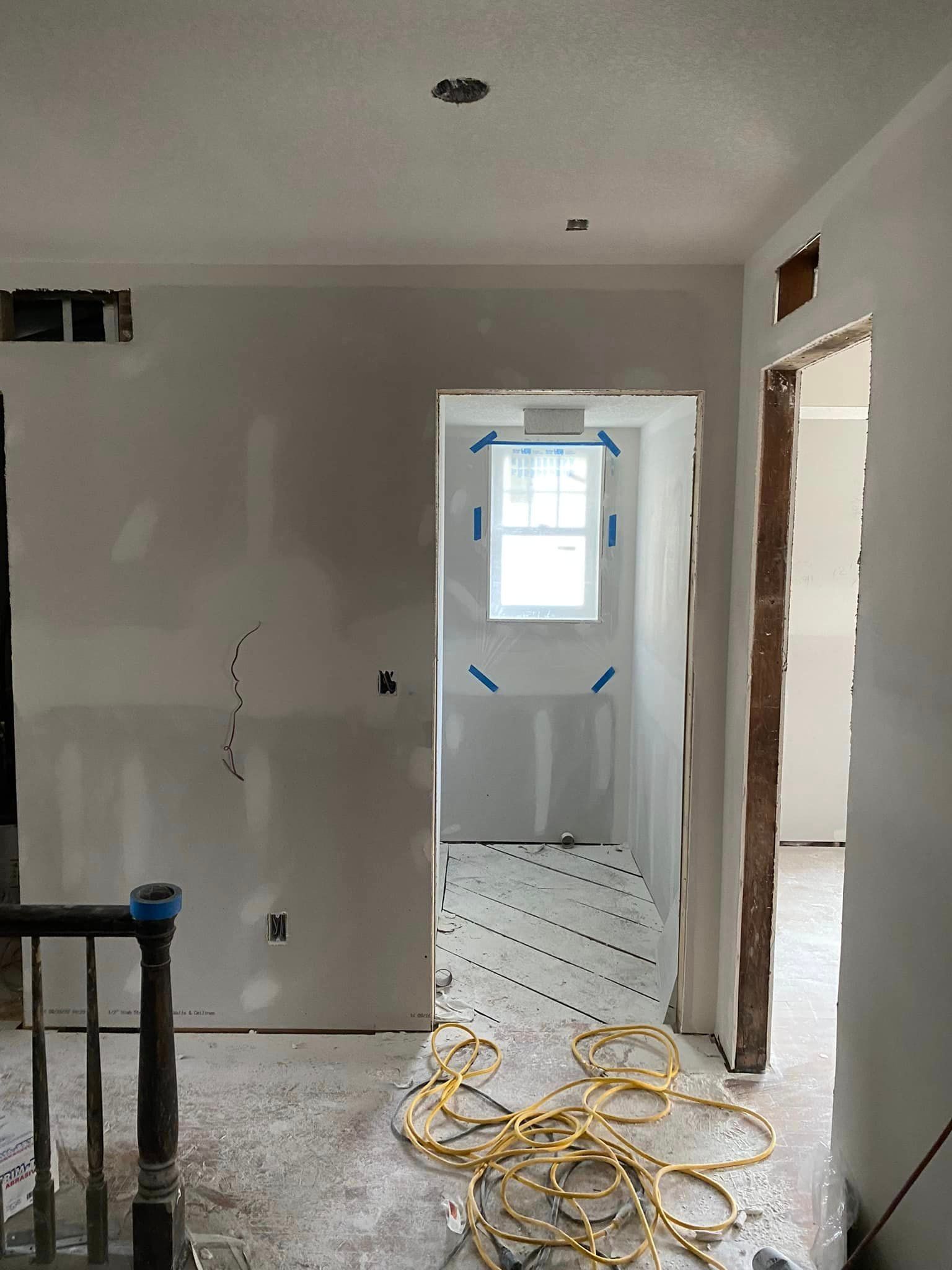 A hallway in a house under construction with a window.