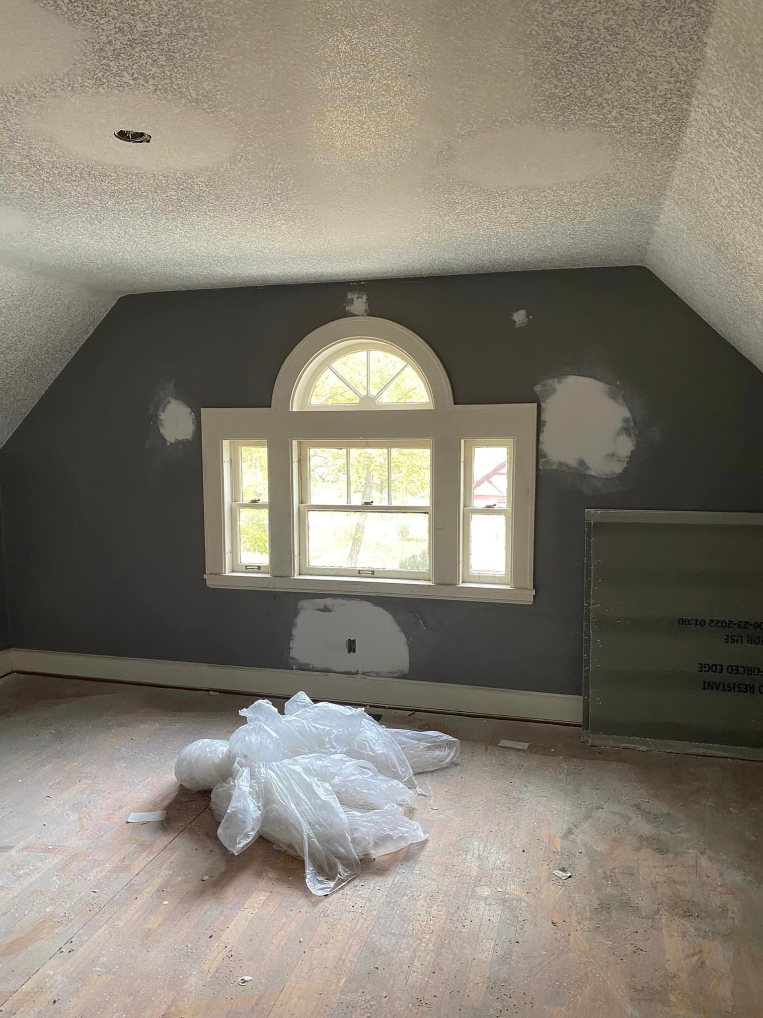 An empty room with a window and a pile of bubble wrap on the floor.