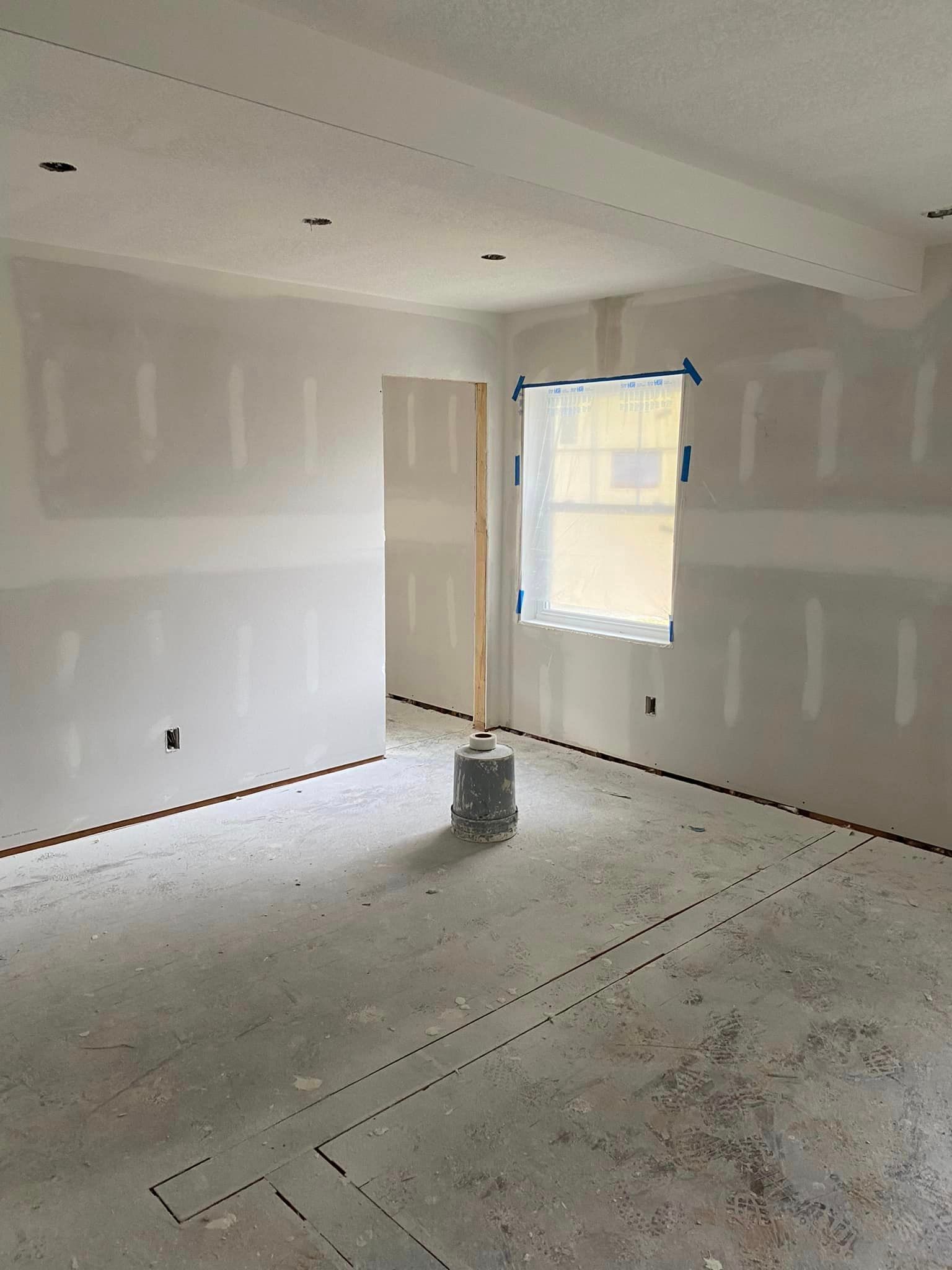An empty room with drywall on the walls and a window.