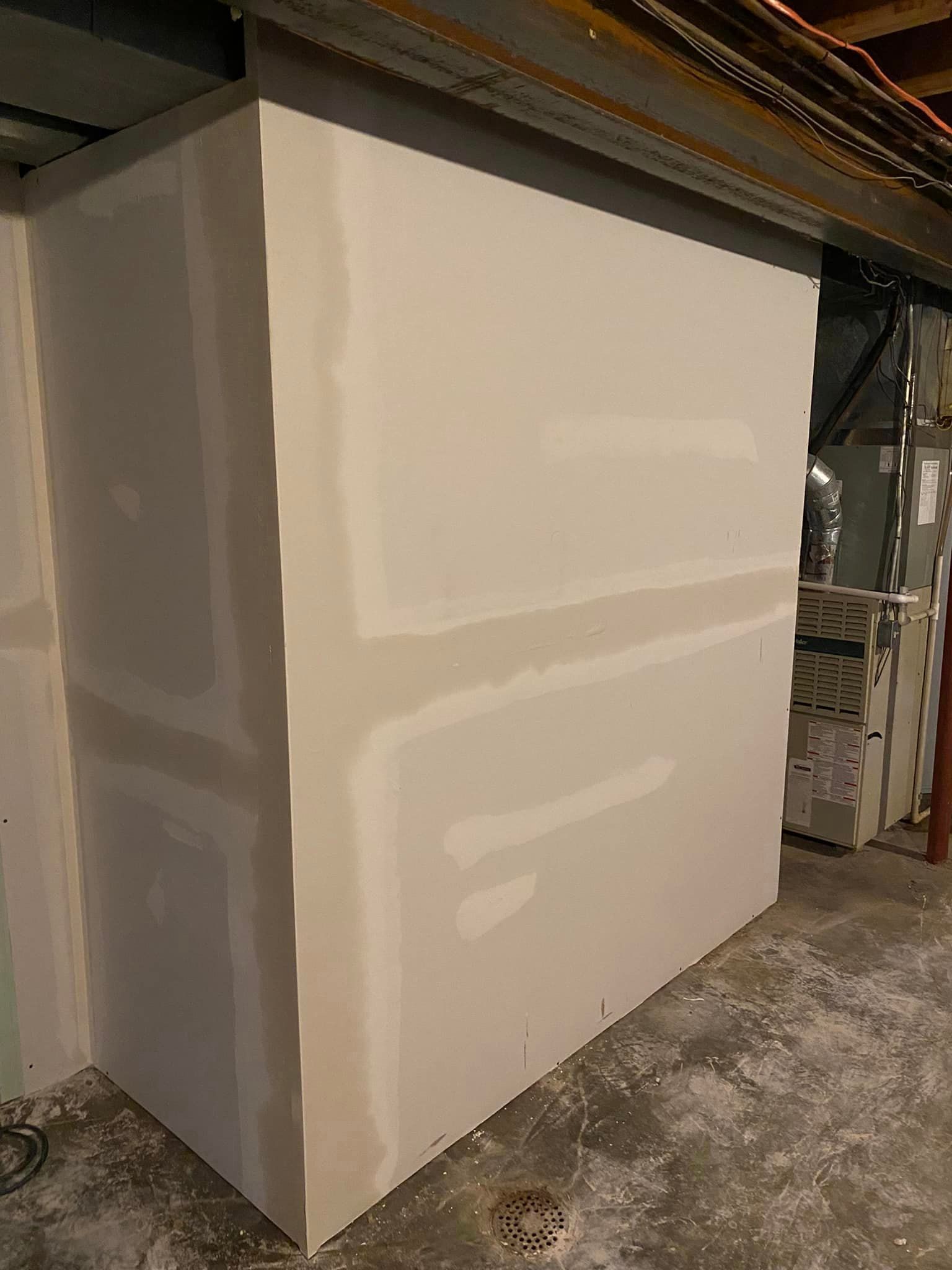 A large piece of drywall is sitting in a basement.