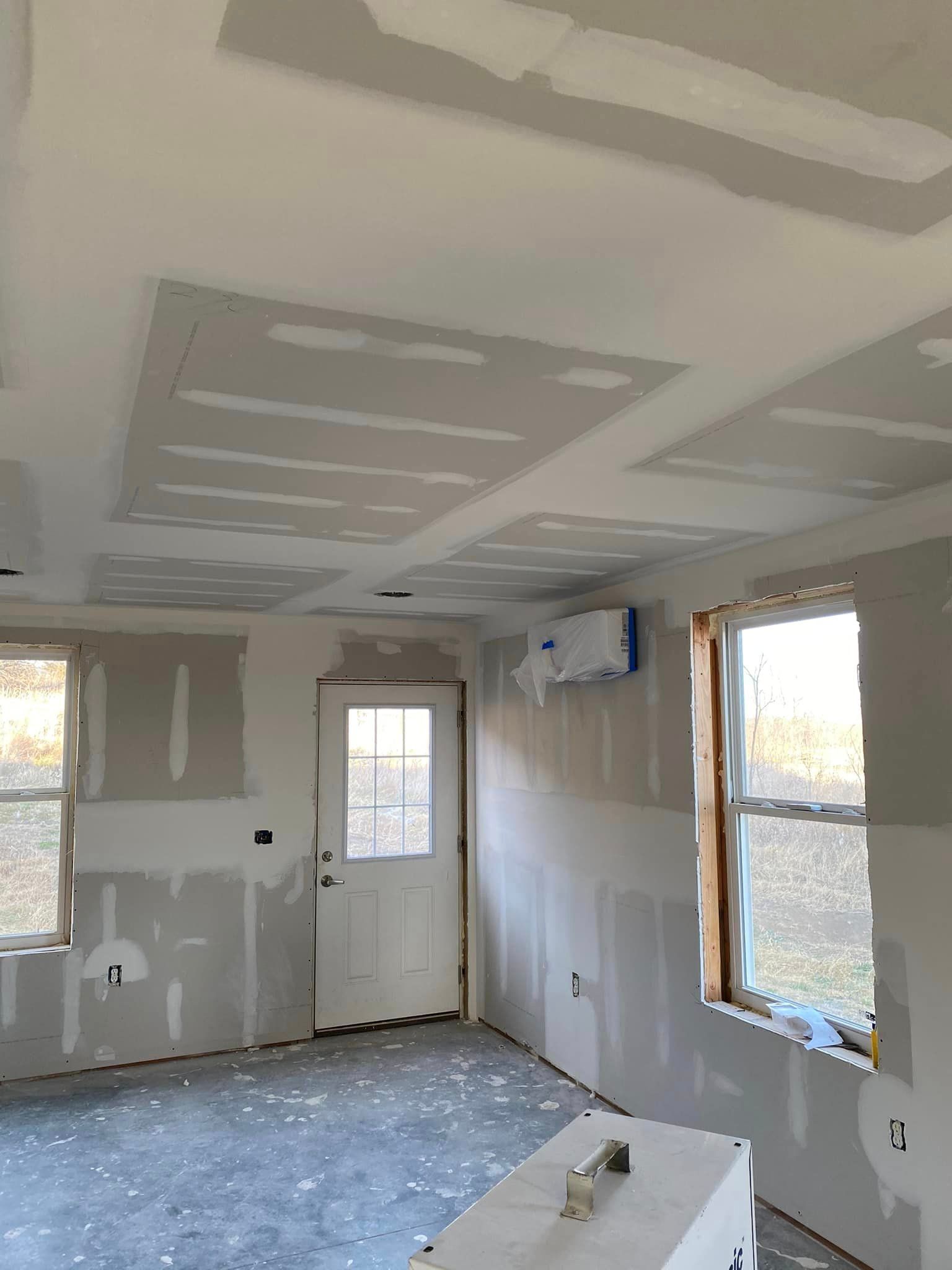 A room with a door and windows is being remodeled.