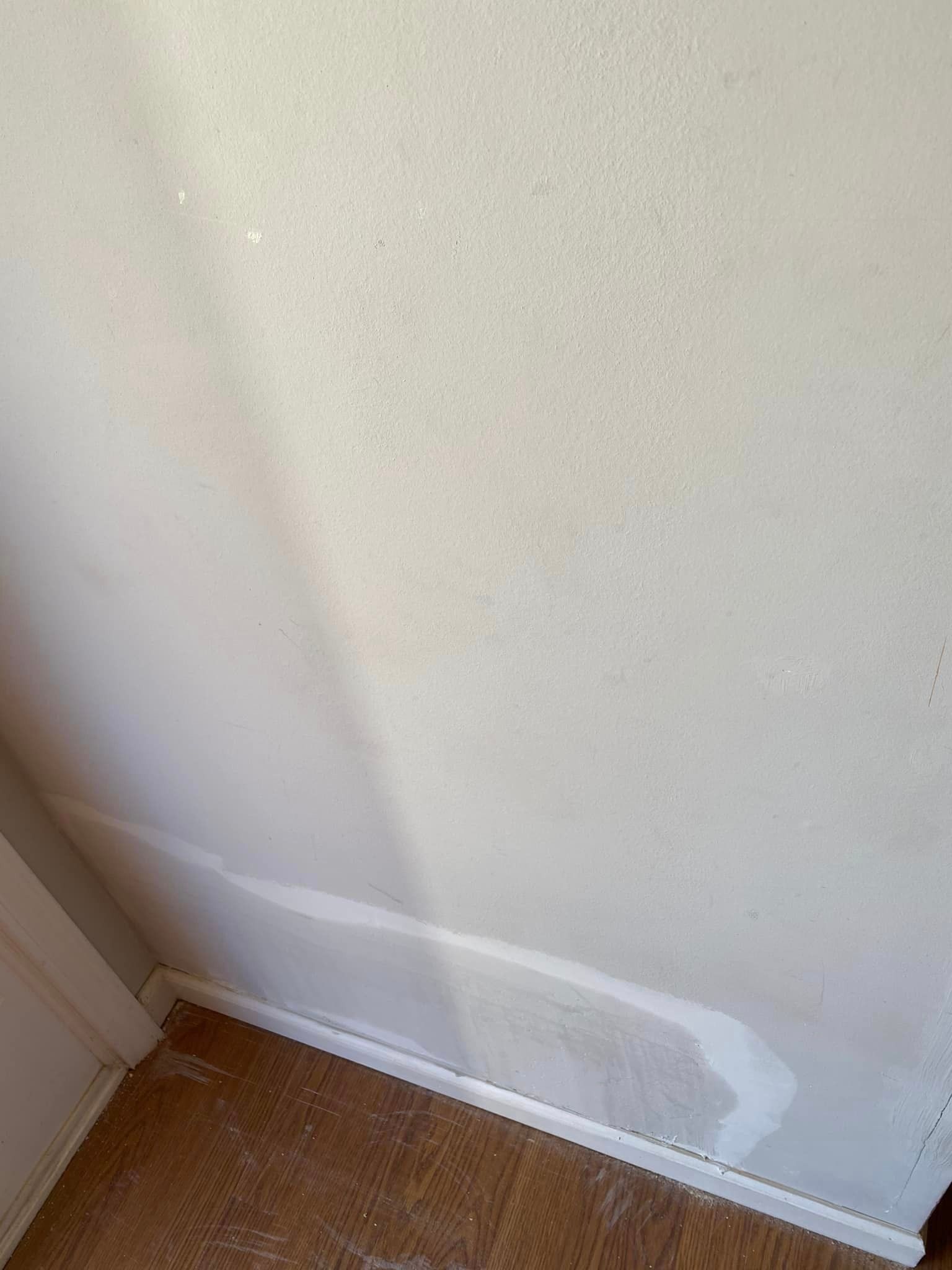 A white wall with a wooden floor in a room.