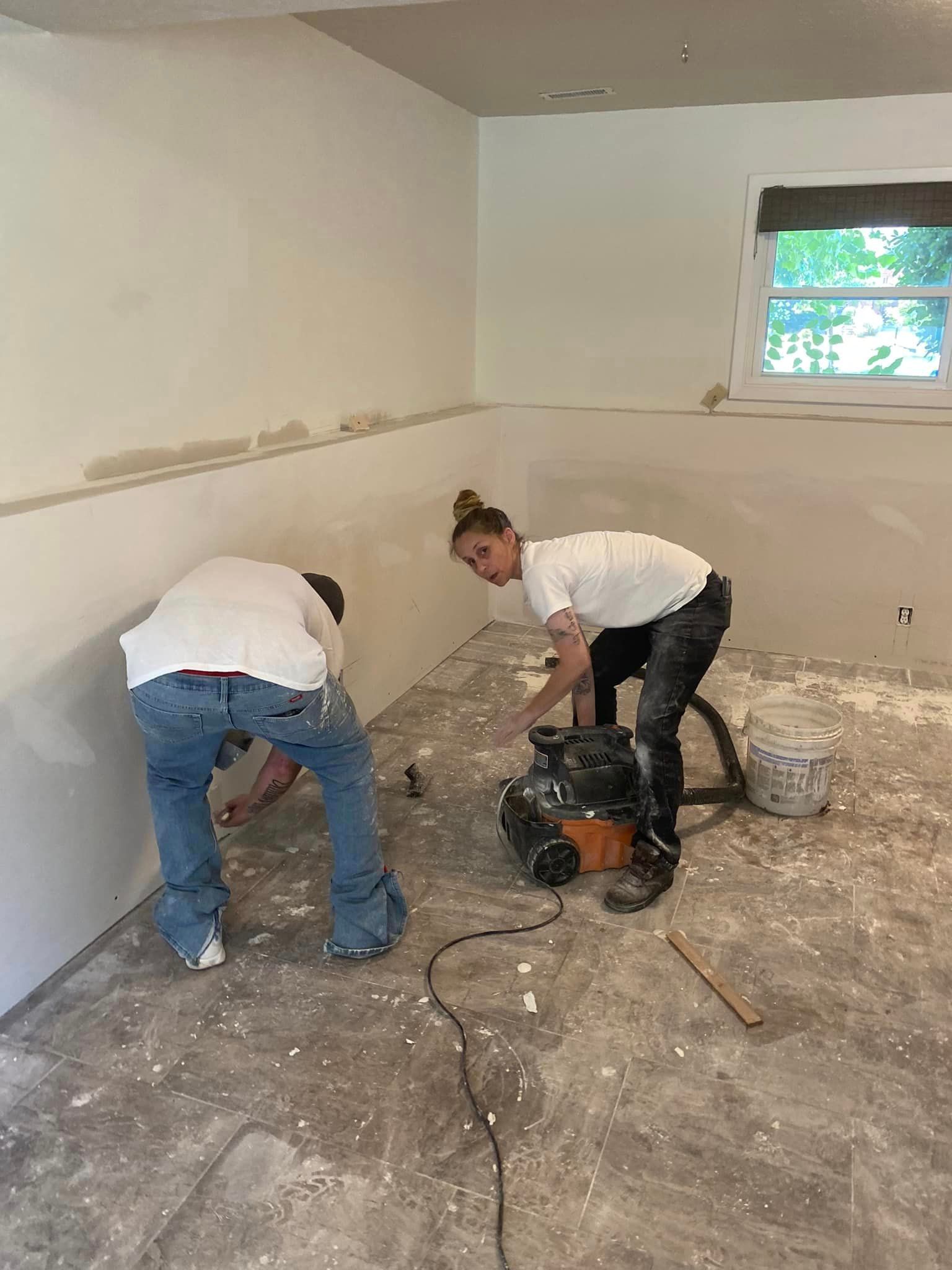 A man and a woman are working on a floor in a room.