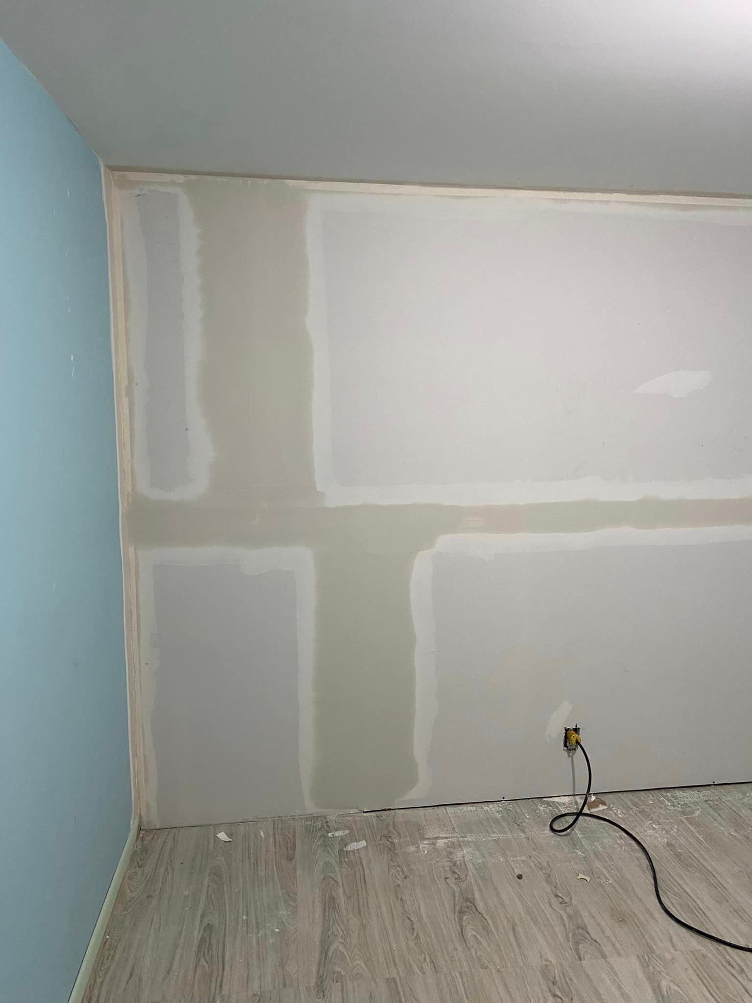 A room with drywall walls and a wooden floor.
