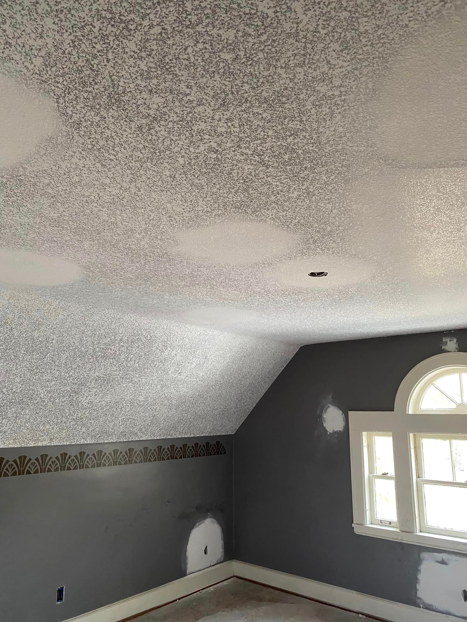 A room with a gray wall and a white ceiling with a window.