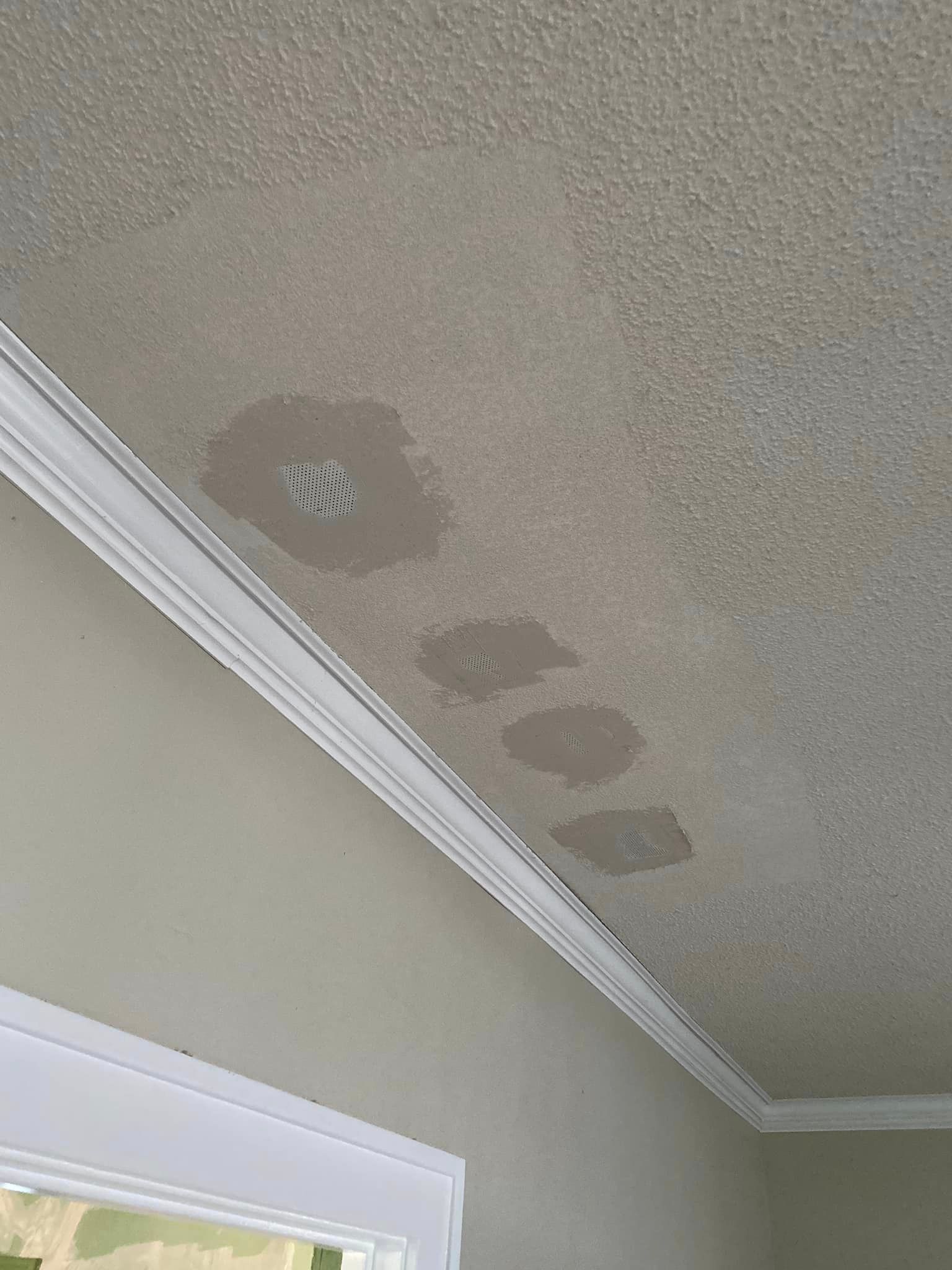 A ceiling with water spots on it in a room next to a door.