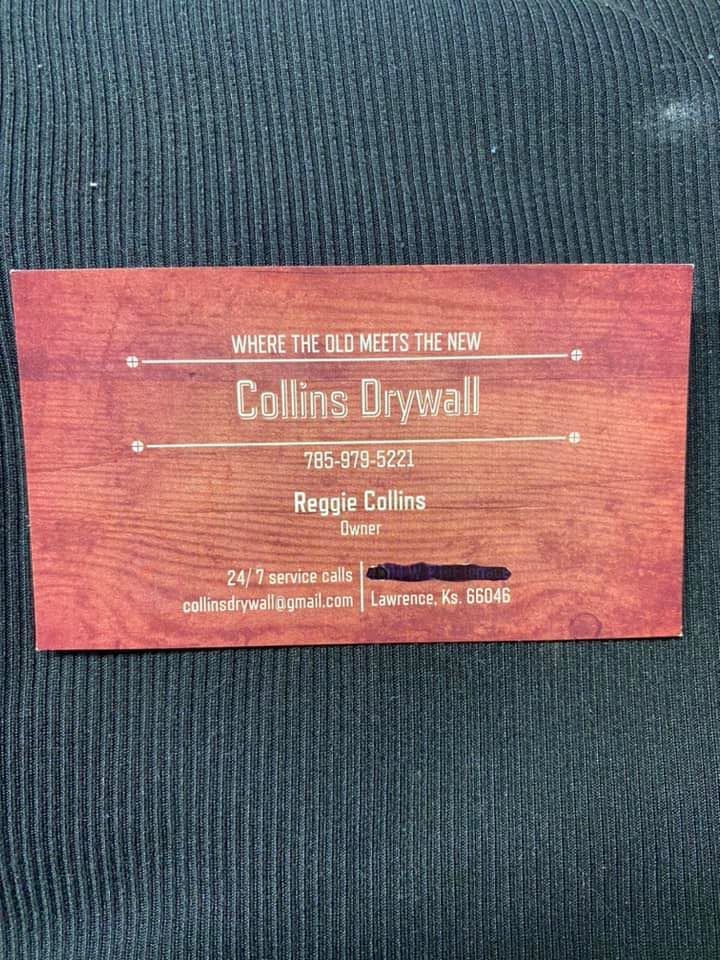 A business card for collins drywall is sitting on a black cloth.