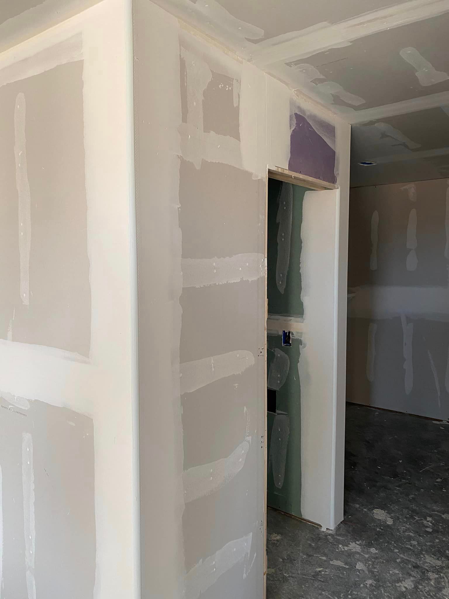 A room with drywall walls and a door in it.