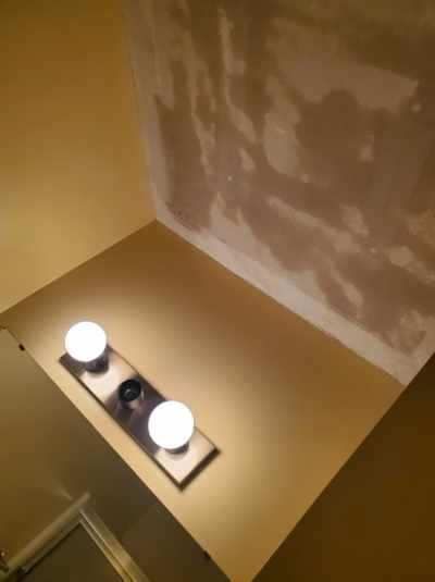A corner of a room with two lights on a shelf.