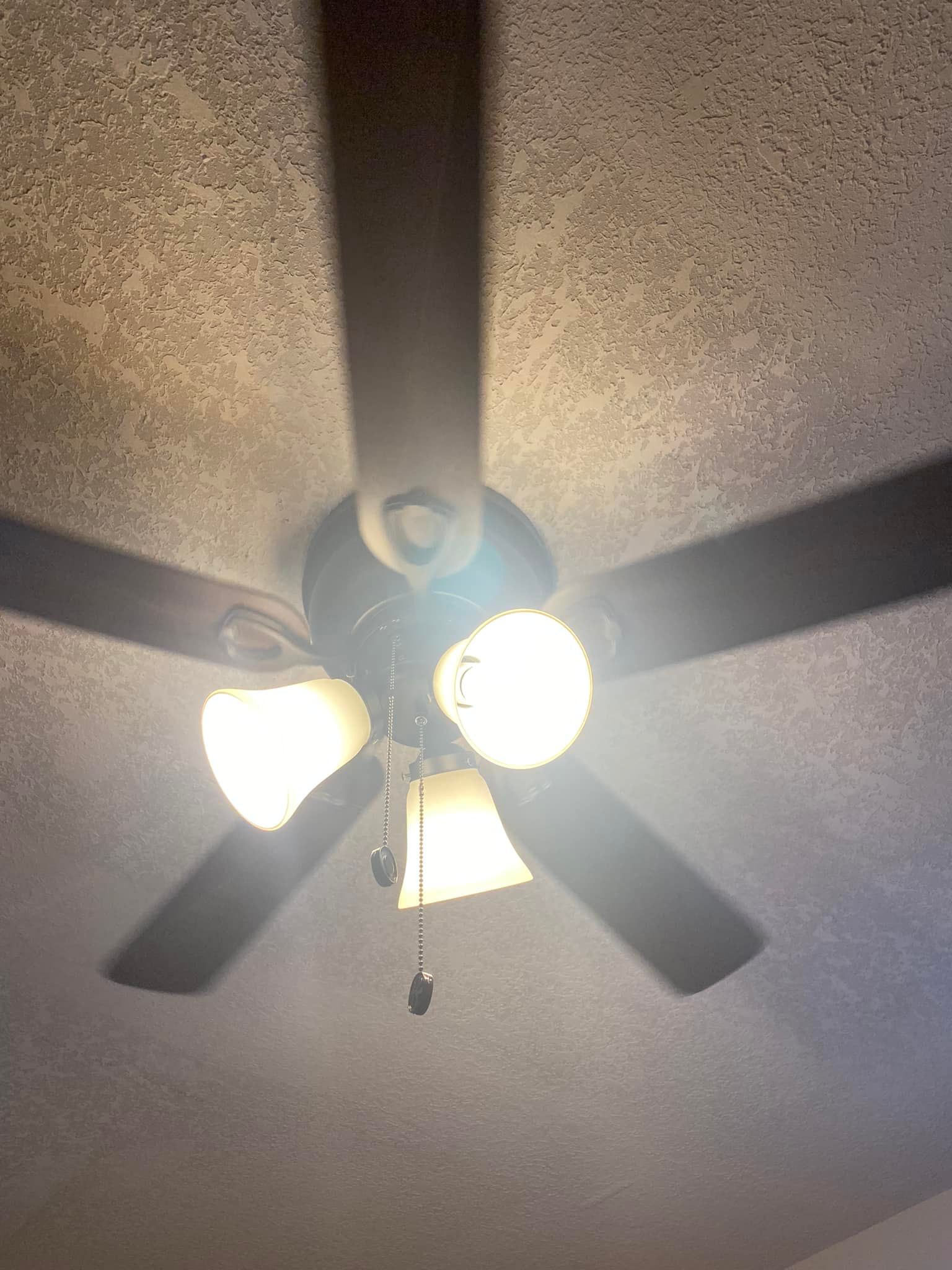 A ceiling fan with lights on it is hanging from the ceiling in a room.