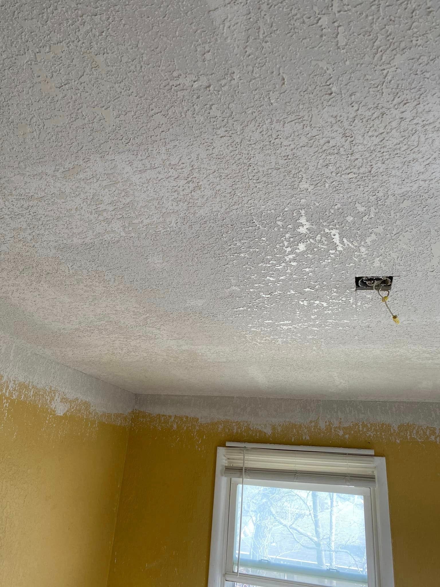 A room with yellow walls and a white ceiling with a window.