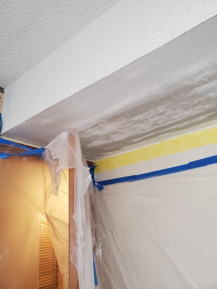 A room with a ceiling that is being painted and covered in plastic.
