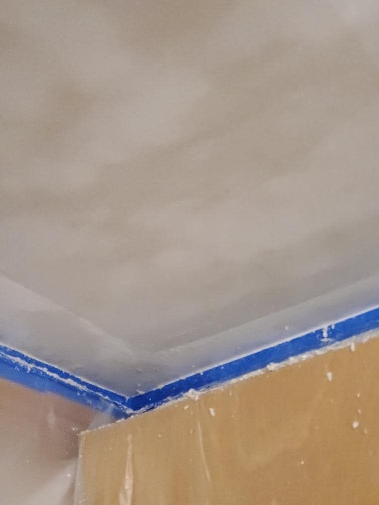A close up of a ceiling with a blue tape on it.