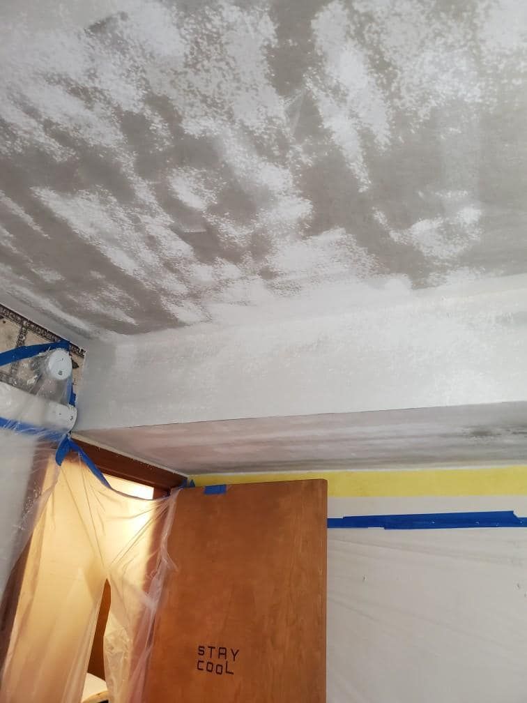 A room with a ceiling that is being painted and a door that says `` stay cool ''.