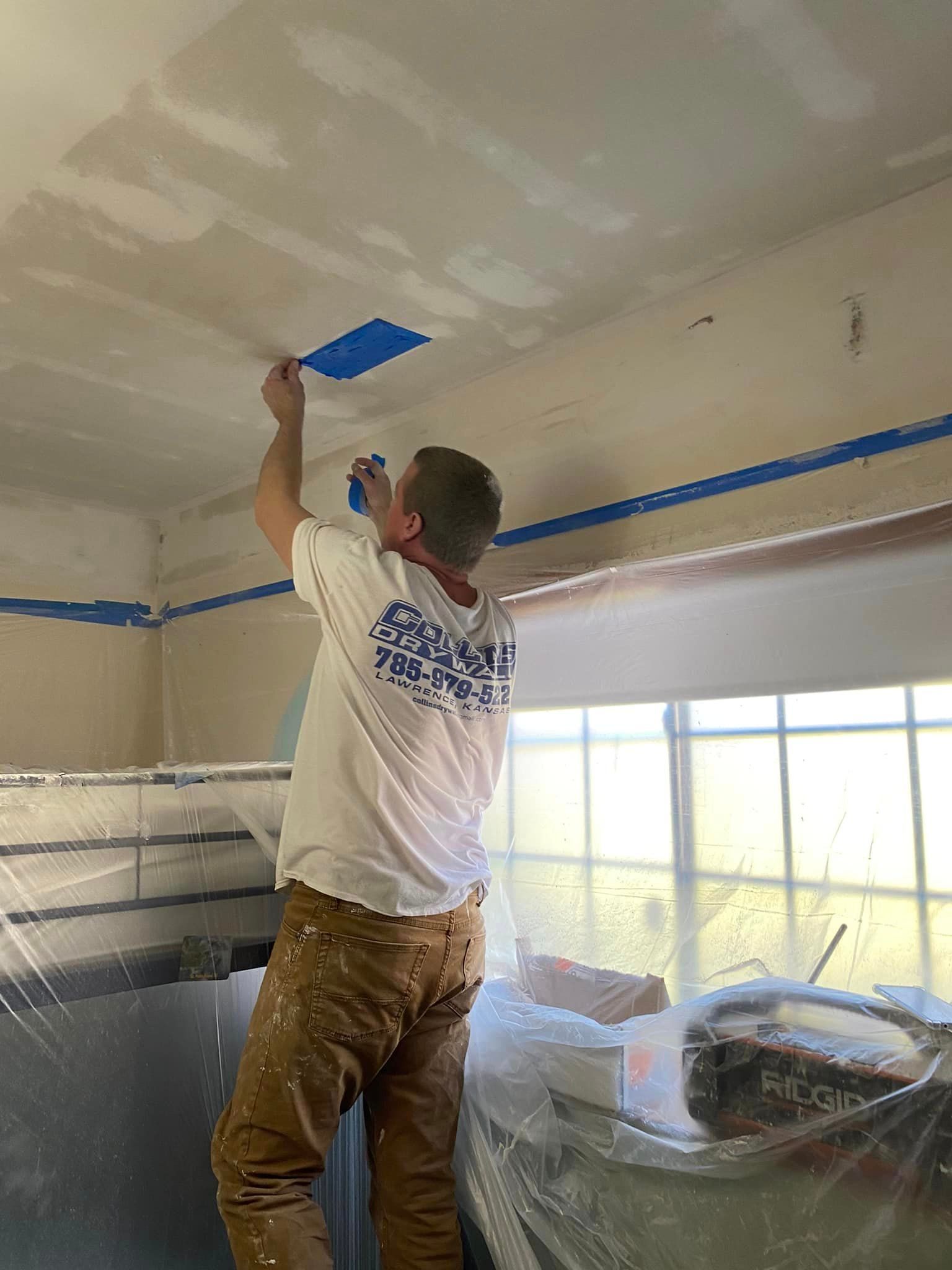 A man is painting the ceiling of a room with a spatula.
