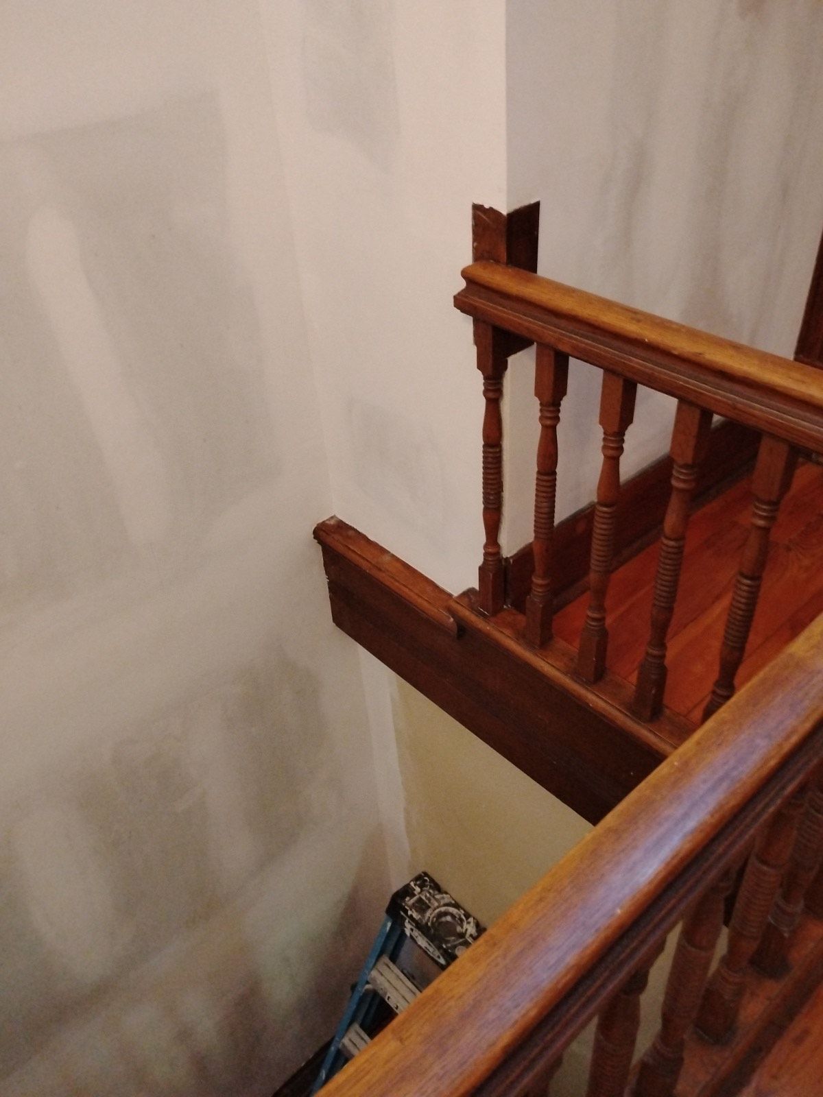 A wooden staircase with a ladder in the corner