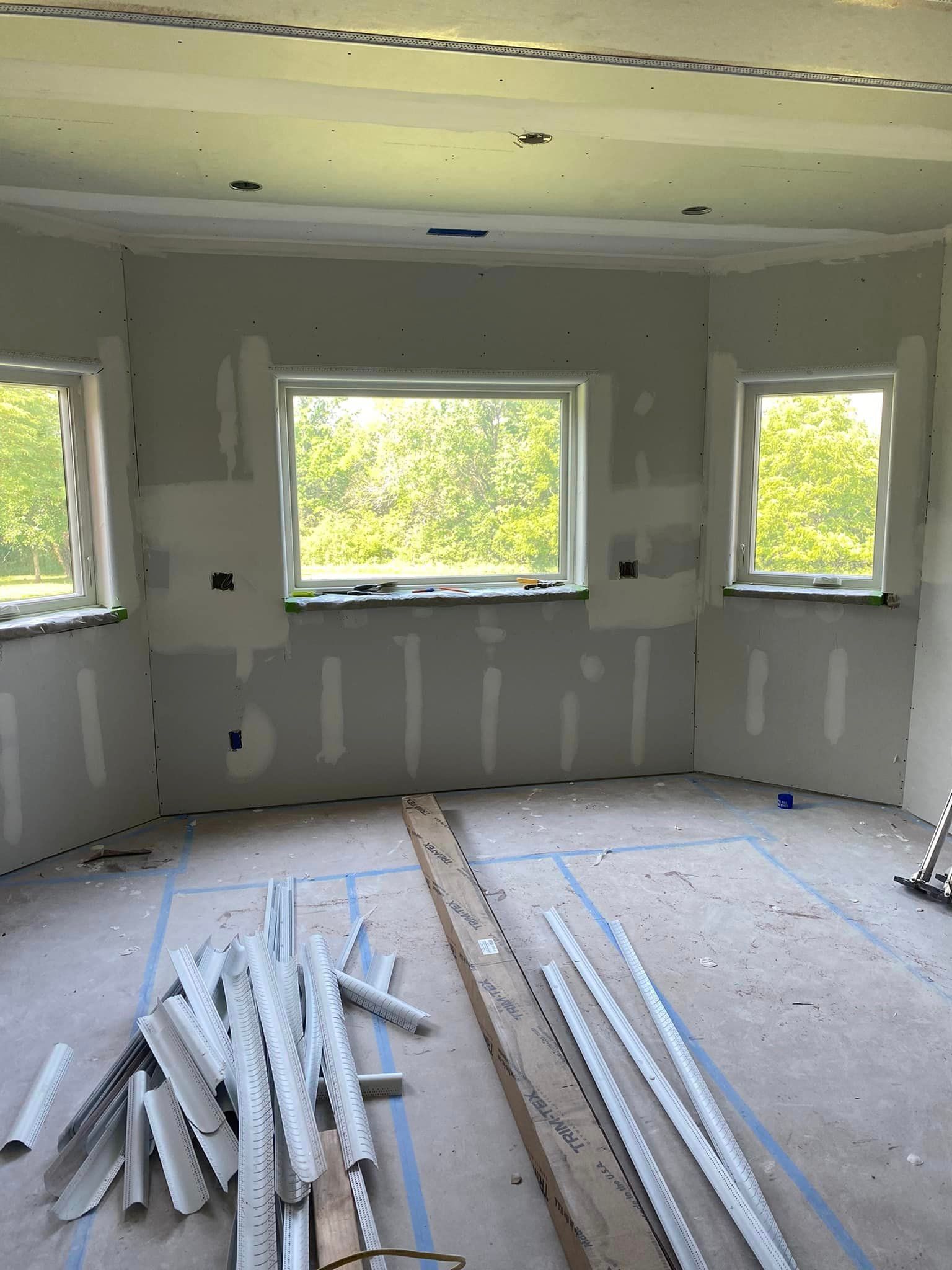 A room with a lot of pieces of wood on the floor and a lot of windows.