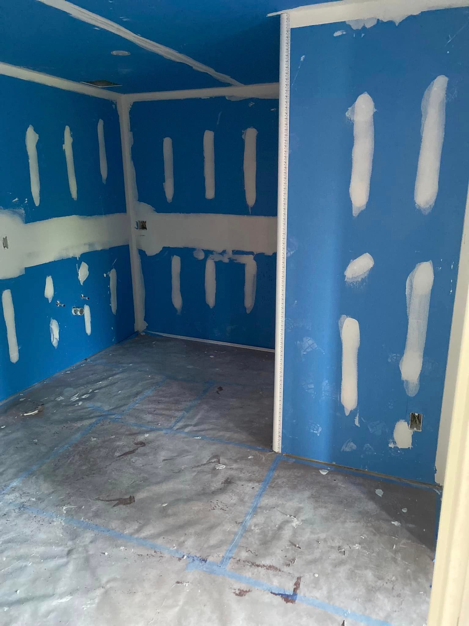 An empty room with blue walls and white trim