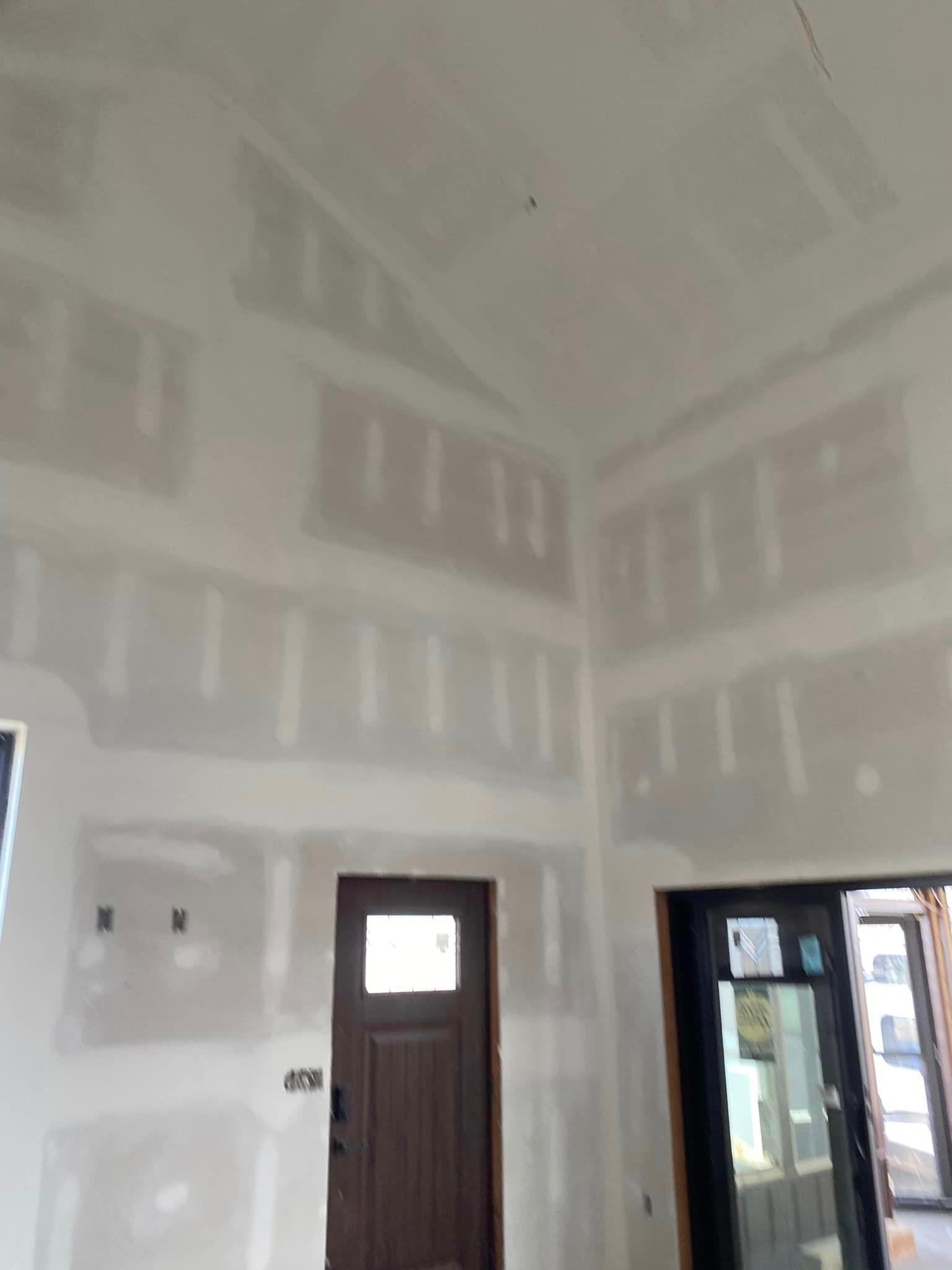 A room with a door and a lot of drywall on the walls.
