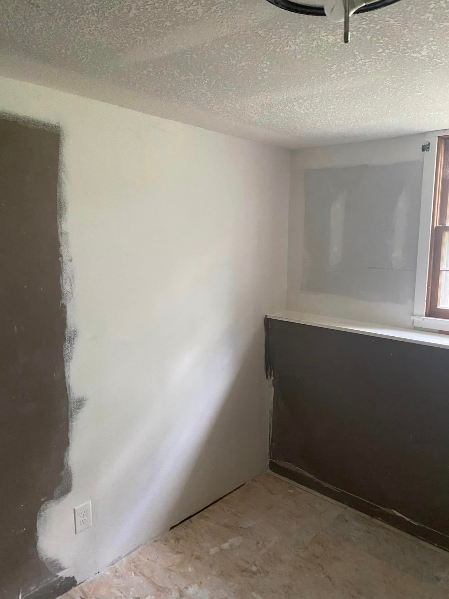 A room with a white wall and a window.