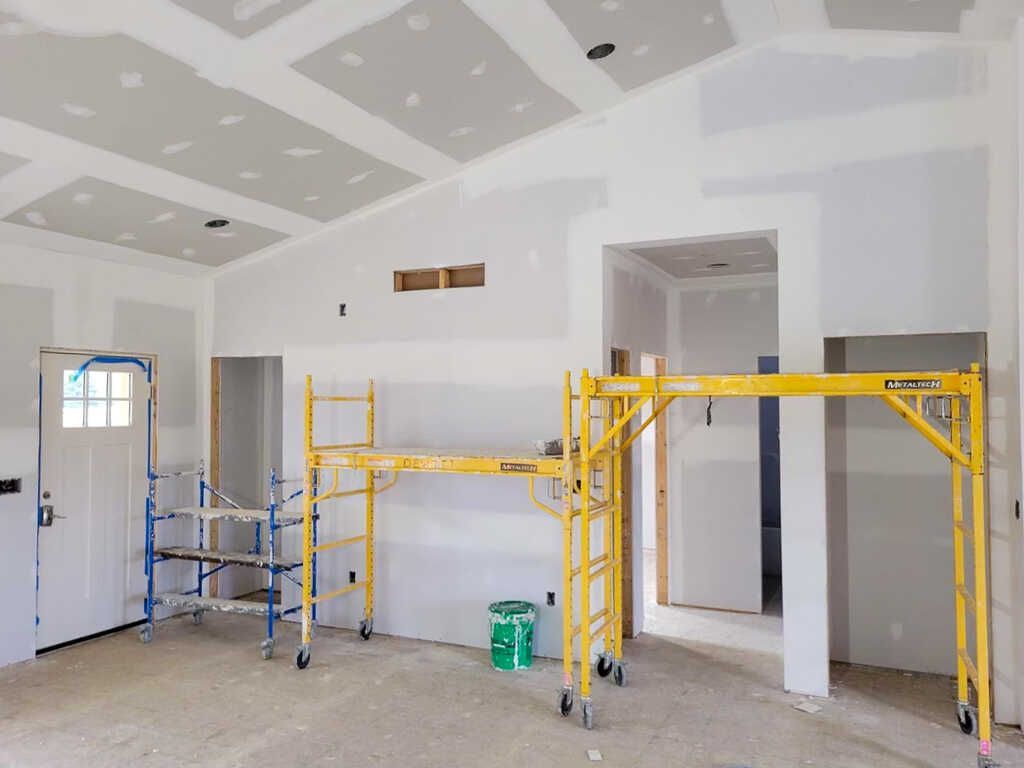 A room is being remodeled with drywall and scaffolding.
