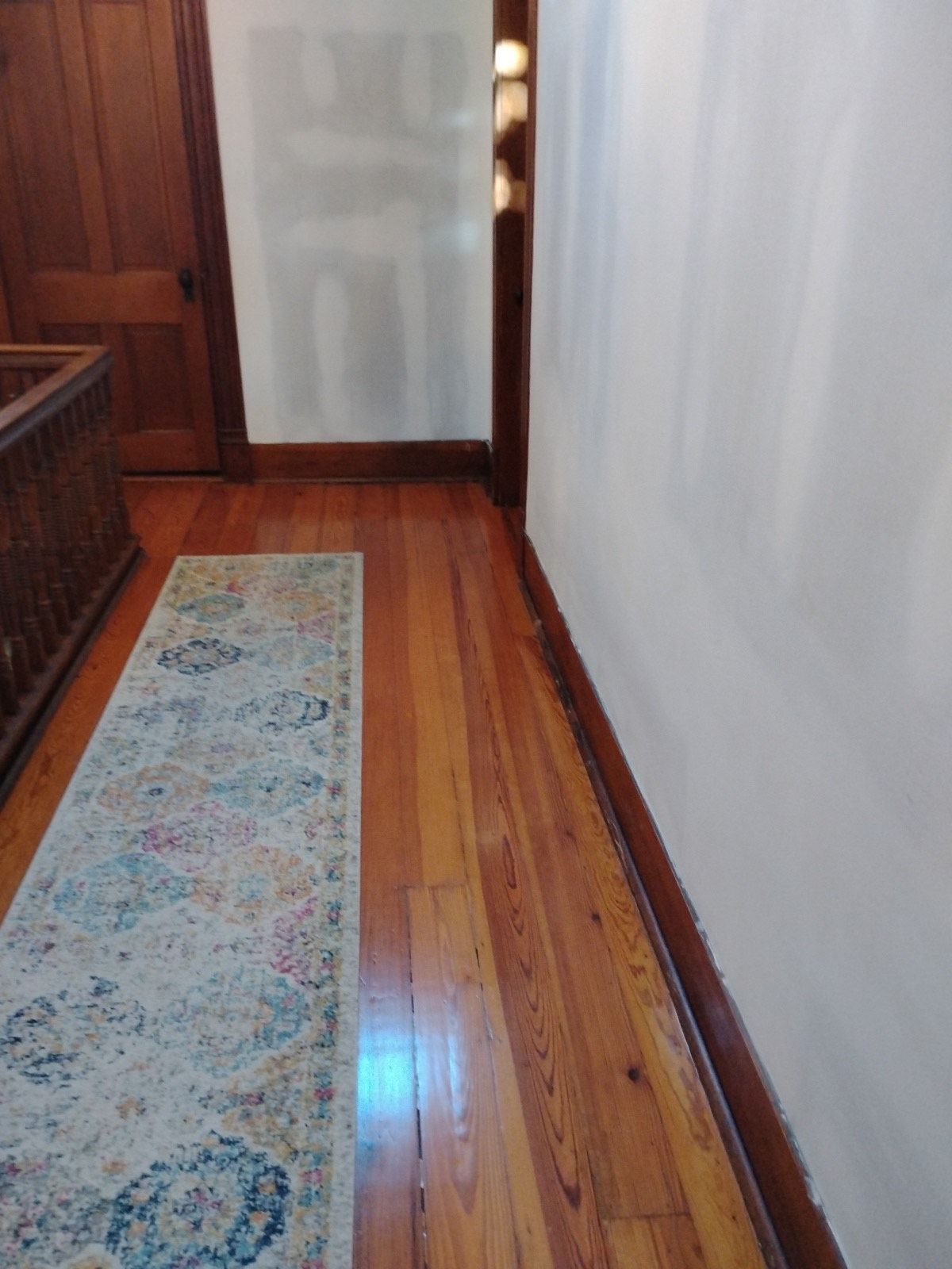 A hallway with hardwood floors and a rug on the floor