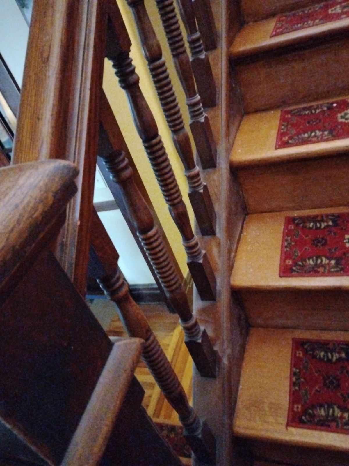A wooden staircase with a rug on the steps