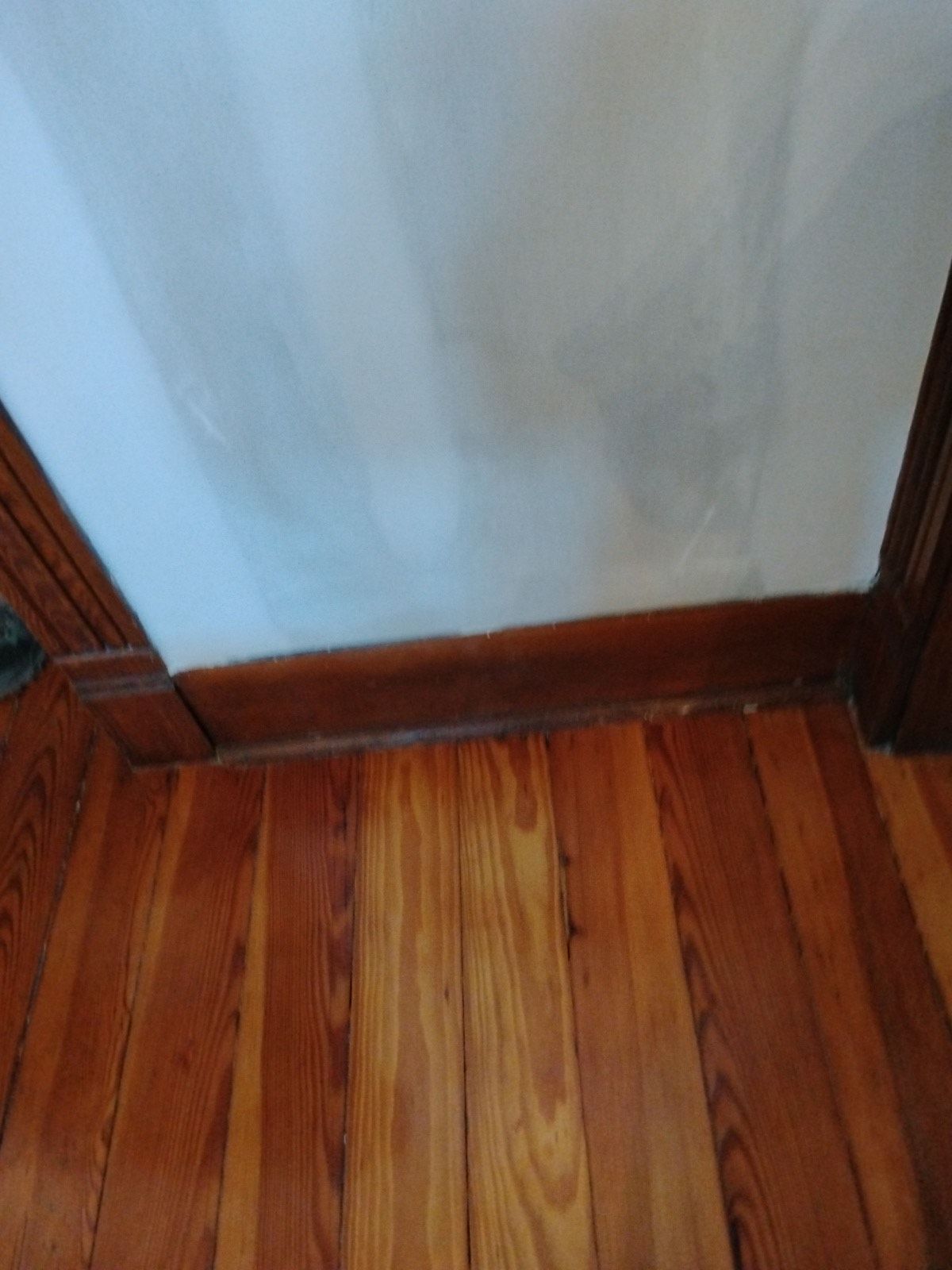 A wooden floor with a white wall in the background