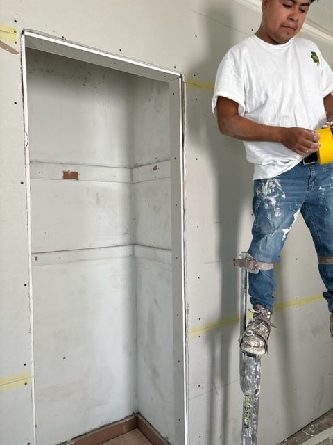A man standing on a ladder holding a yellow tape