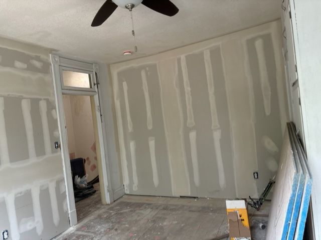 A room with drywall walls and a ceiling fan.