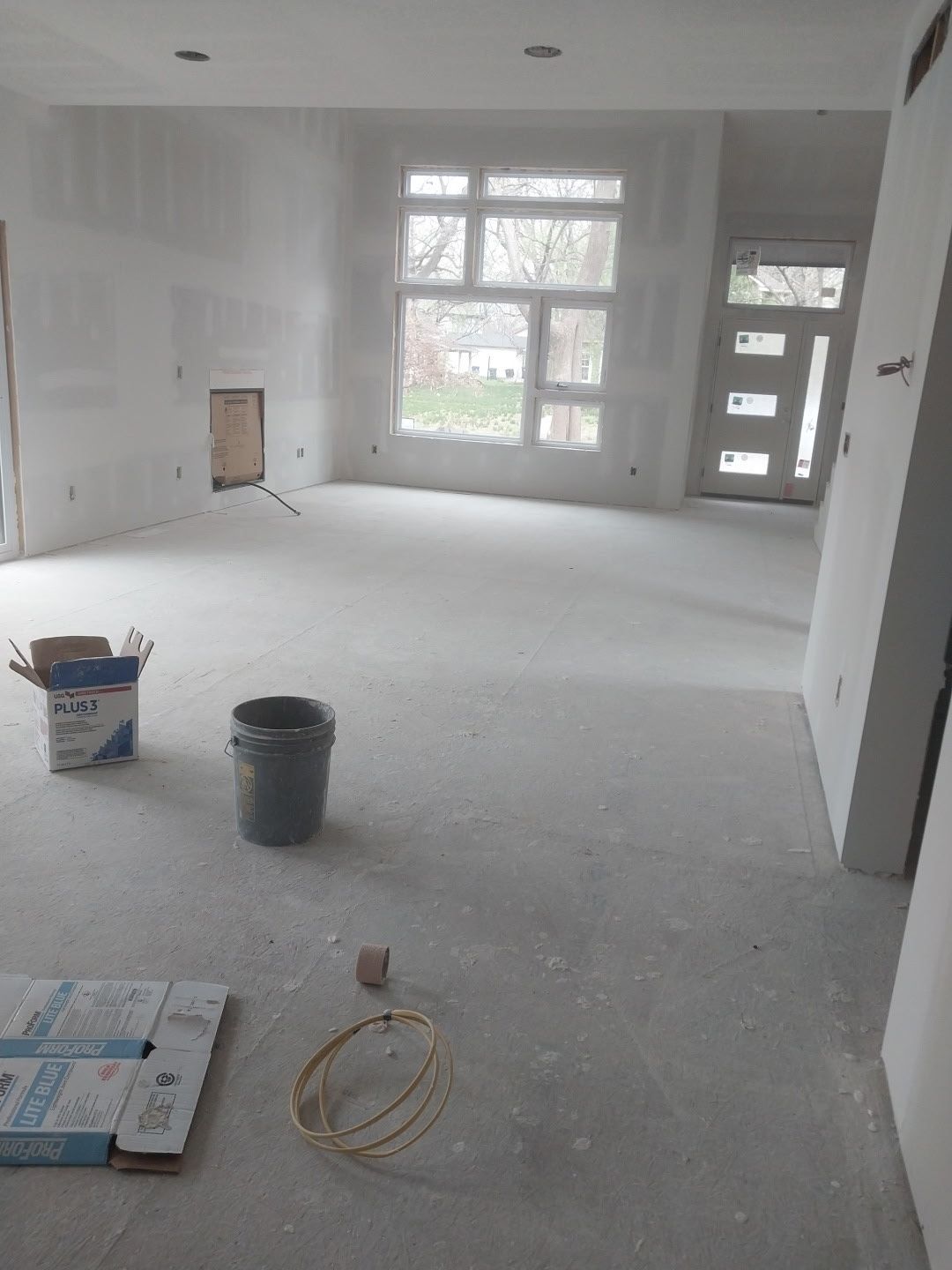 A large empty room with a bucket and boxes on the floor.