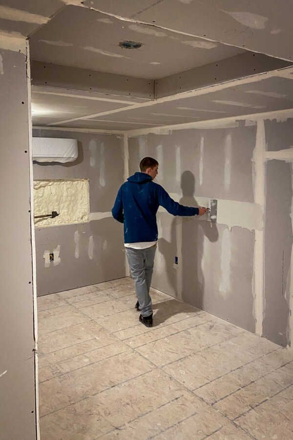 A man is plastering a wall in a room.