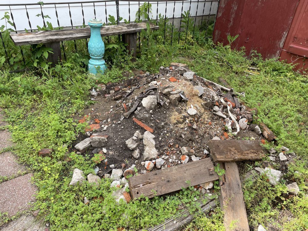 A pile of rocks and bricks is sitting in the grass next to a bench.