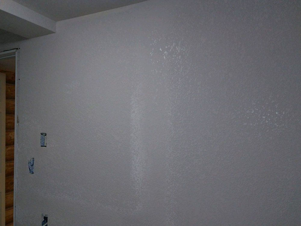 A white wall in a room with a wooden door.