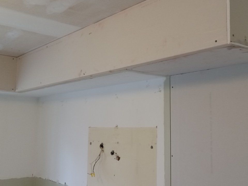 A white wall with a wooden beam hanging from it.